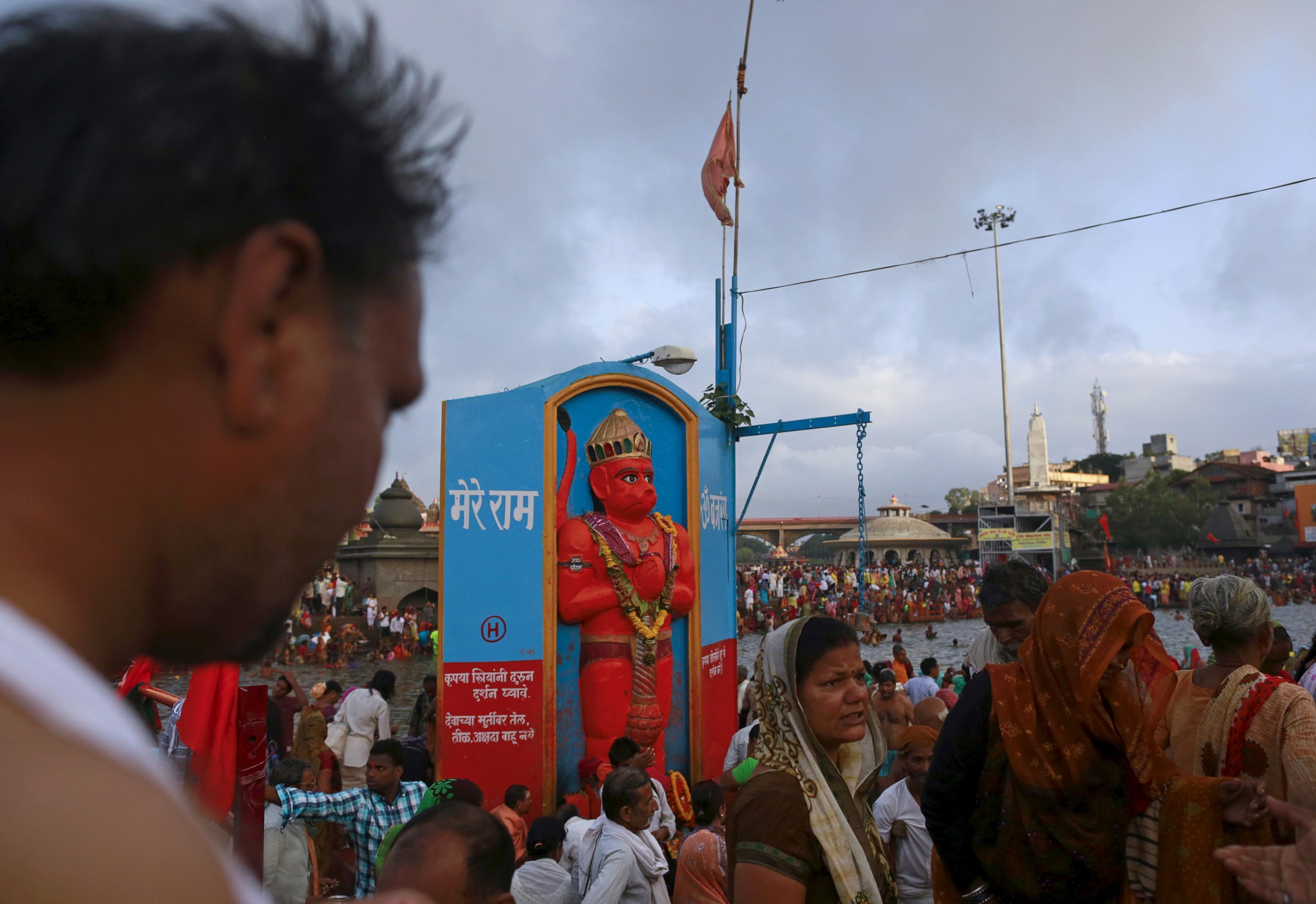 Devotees walk past an Hanuman idol on the banks of Godavari river during "Kumbh Mela" or the Pitcher Festival in Nashik