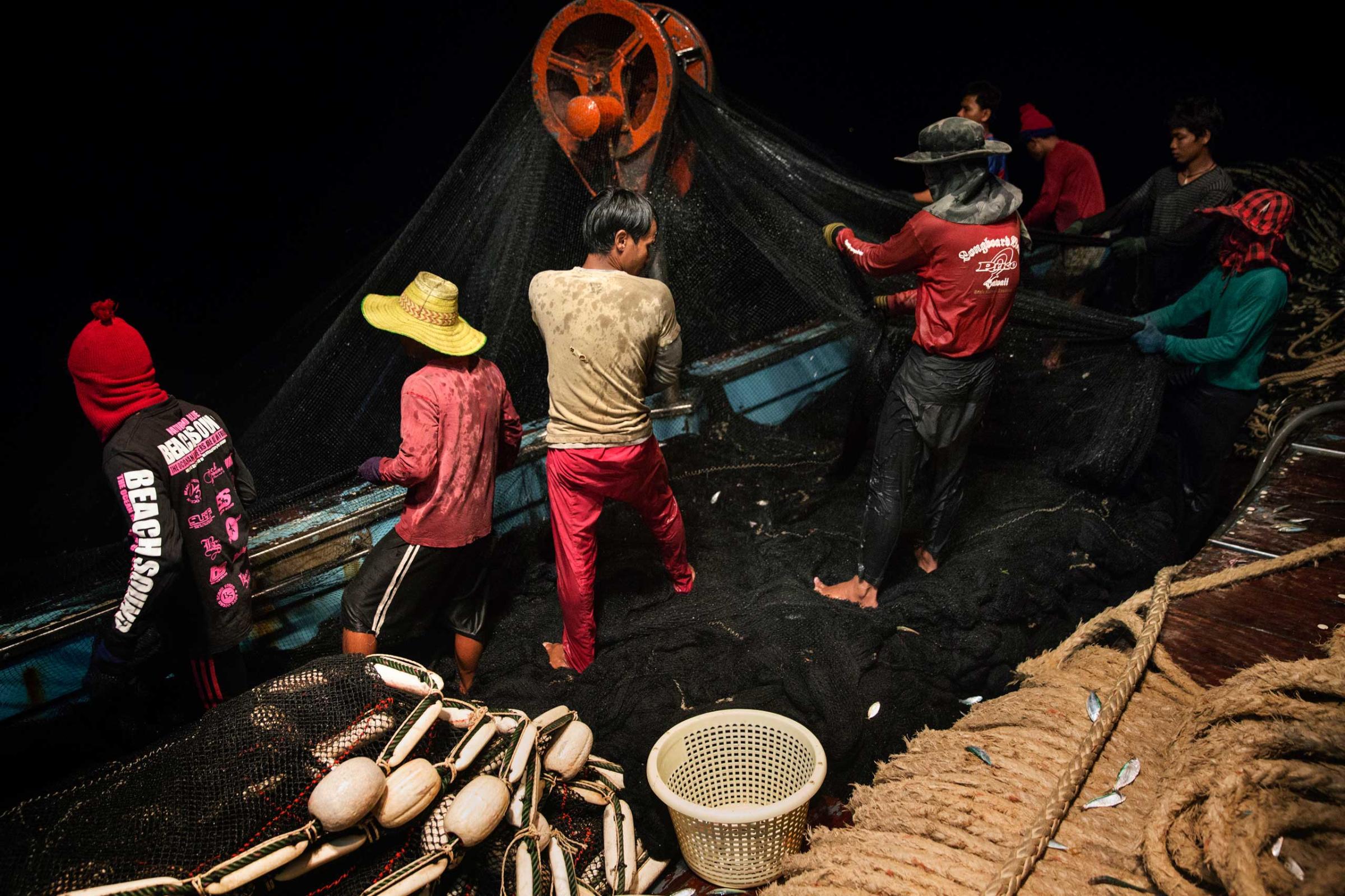 Cambodian migrant fishermen haul in the net on a Thai flagged fishing boat in the Gulf of Thailand.
