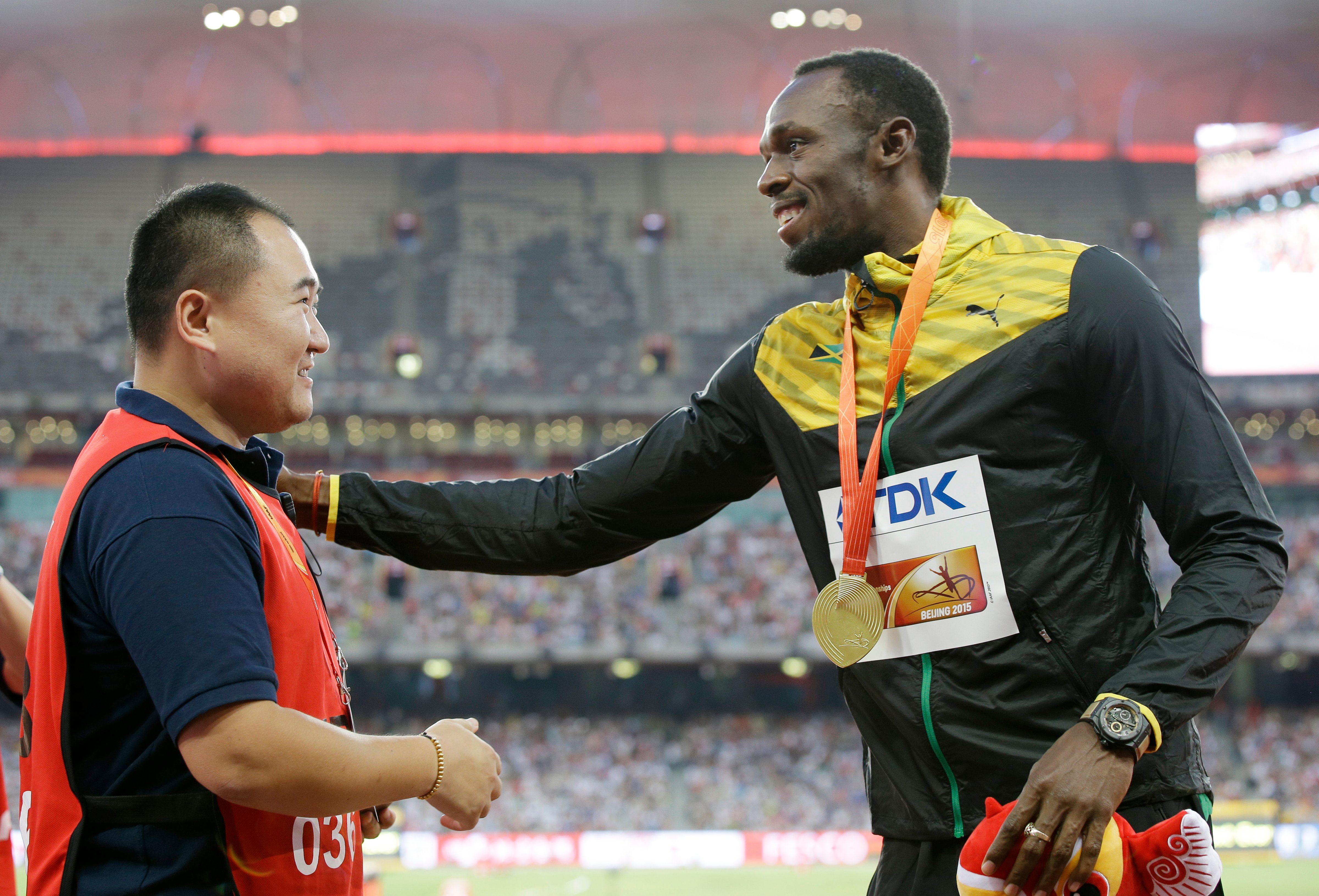 Jamaica's Usain Bolt, left, receives a gift from the cameraman who hit Bolt with a segway after the 200m final on Aug. 27. (Kin Cheung—AP)