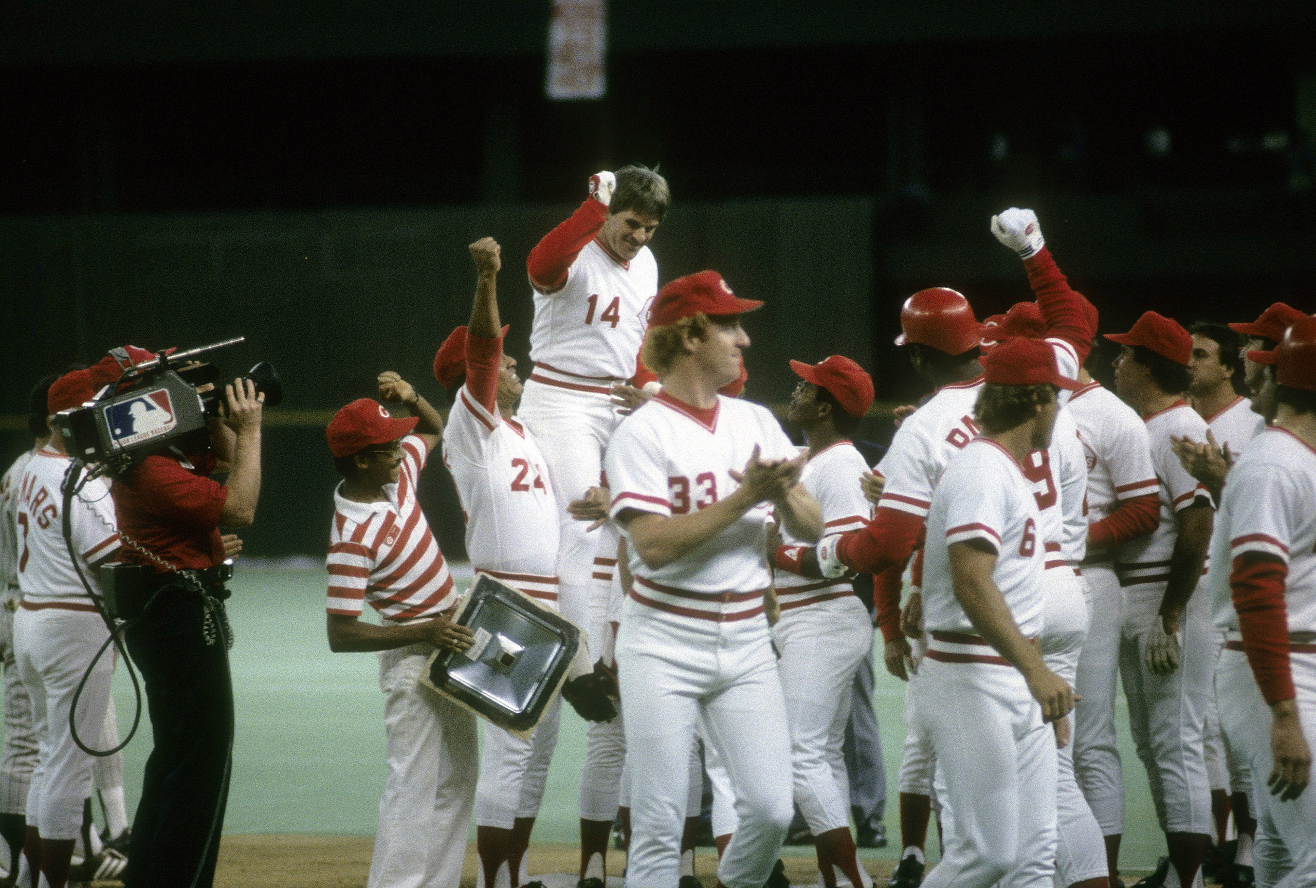 Outfielder Pete Rose #14 of the Cincinnati Reds is surrounded by teammates and lifted in the air by Tony Perez #24, after surpassing Ty Cobb with  his 4,192th hit.
