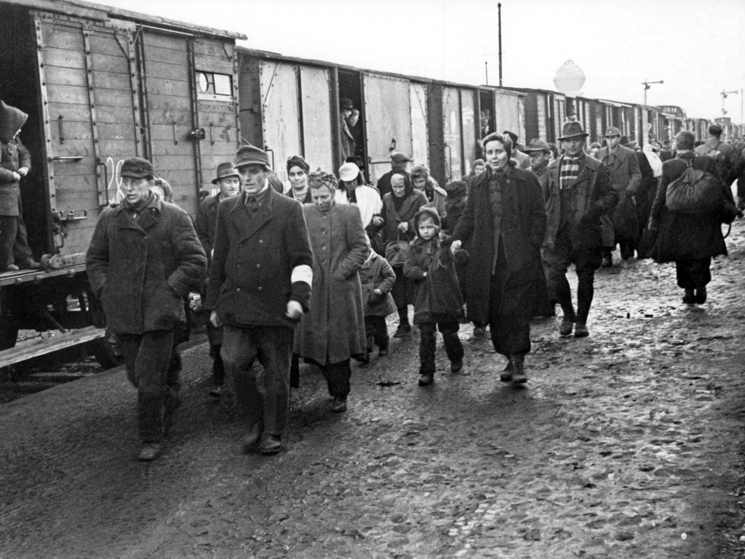 An attendant with white brassard (front, r) accompanies newly arrived refugees, in January 1946, through the refugee camp in Bebra.