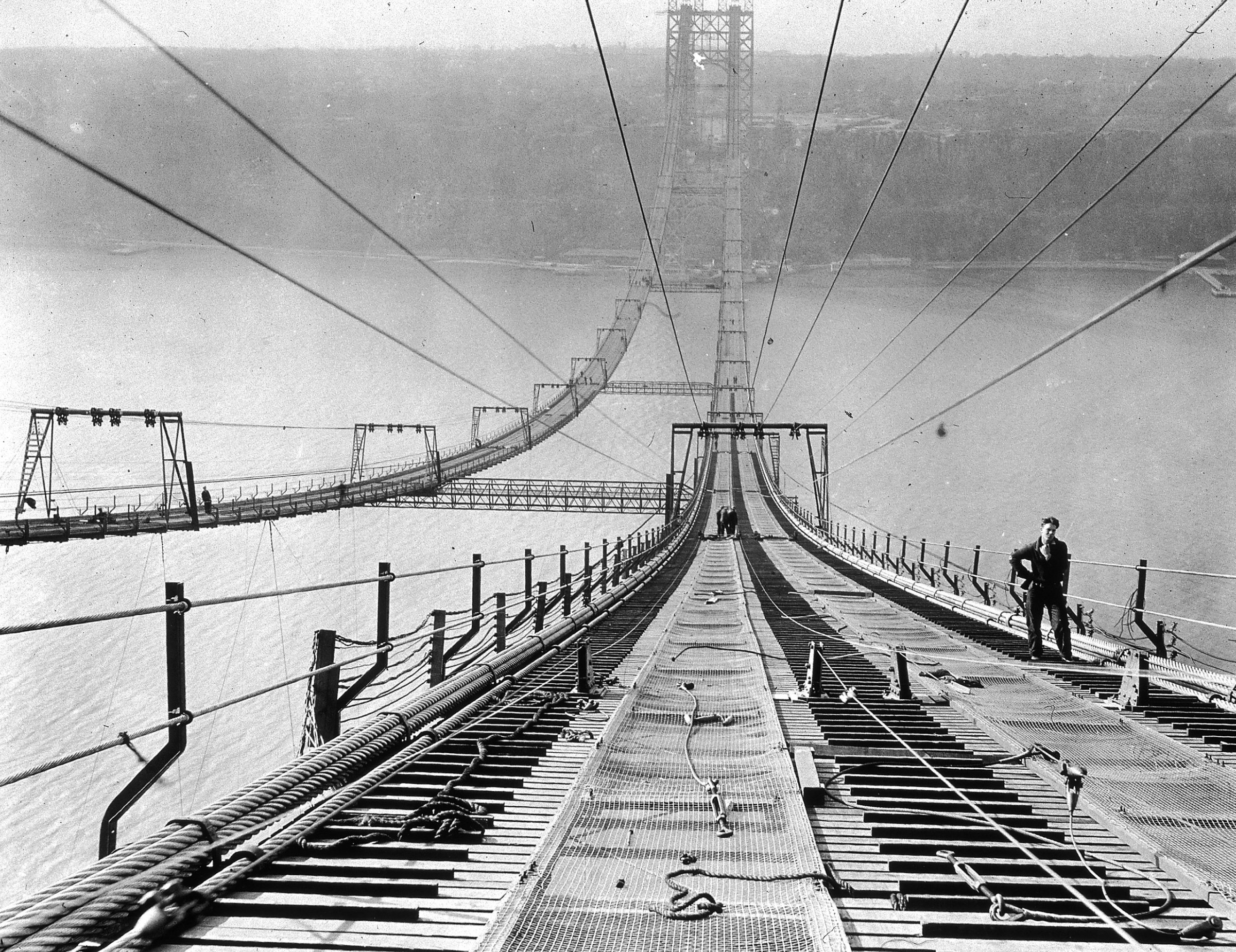 Full-length image of a worker pausing near the top of the George Washington Bridge during its construction, New York City. Circa 1930.