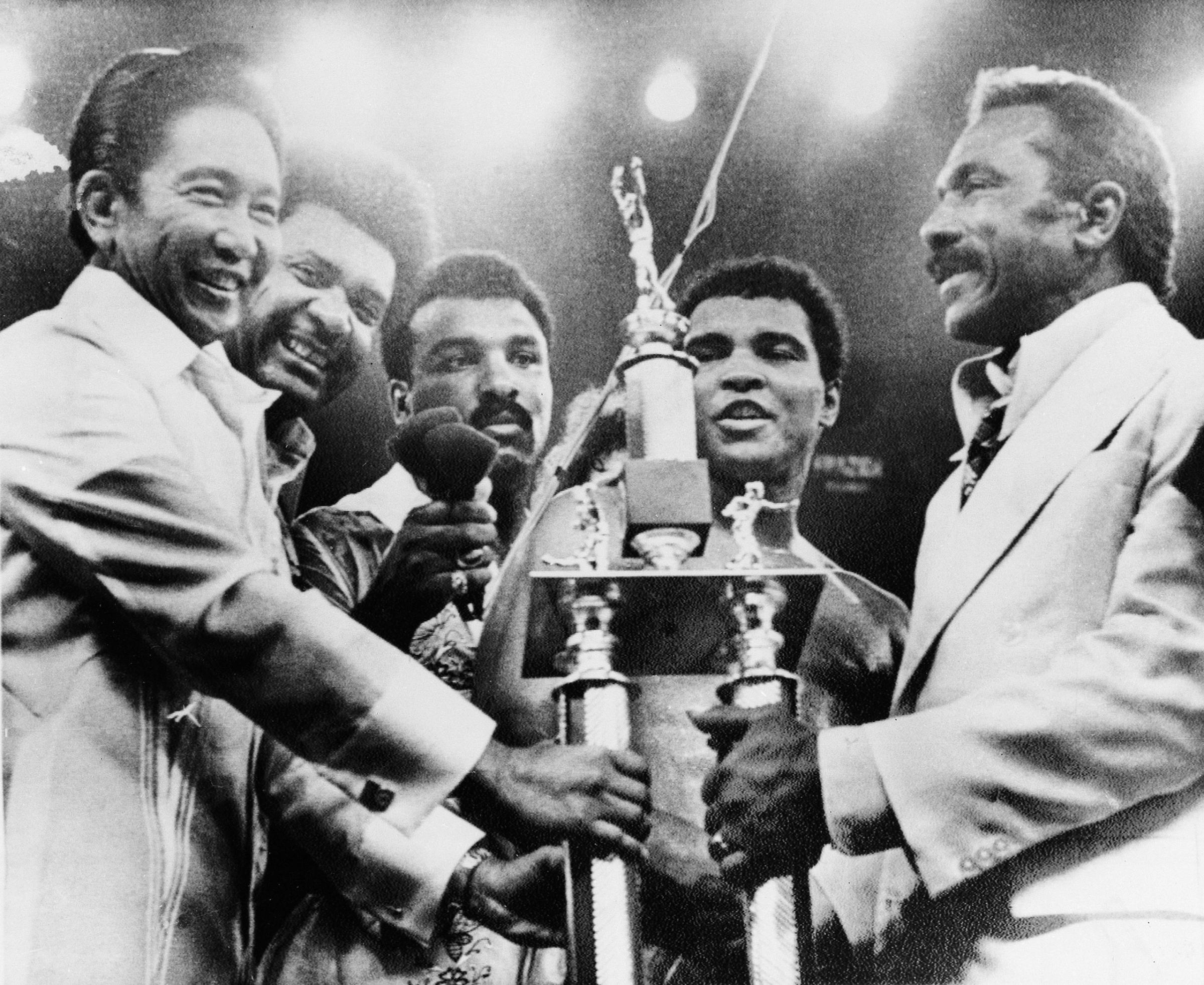 President Ferdinand Marcos, left, of the Philippines, presents the President's Trophy to heavyweight champion Muhammad Ali, second from right, after Ali defeated Joe Frazier in their "Thrilla in Manila" fight at the Coliseum in Manila, October 1, 1975. Posing from left are, President Marcos; promoter Don King; Ali's brother, Rahman; Ali, and his father Cassius Marcellus Clay Sr., right.