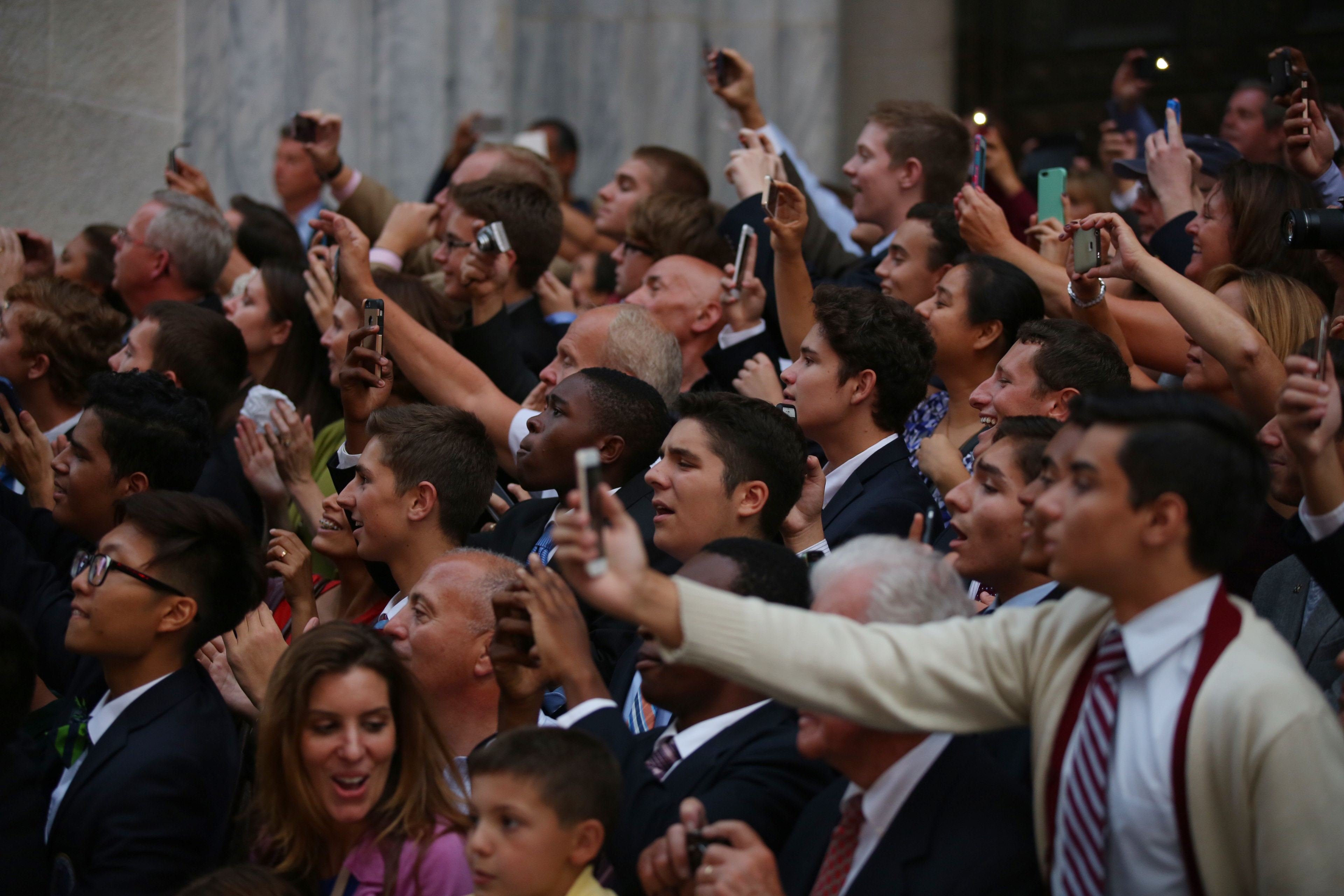 People in the crowds outside of St. Patrick's Cathedral take pictures in New York City, on Sept. 24, 2015.