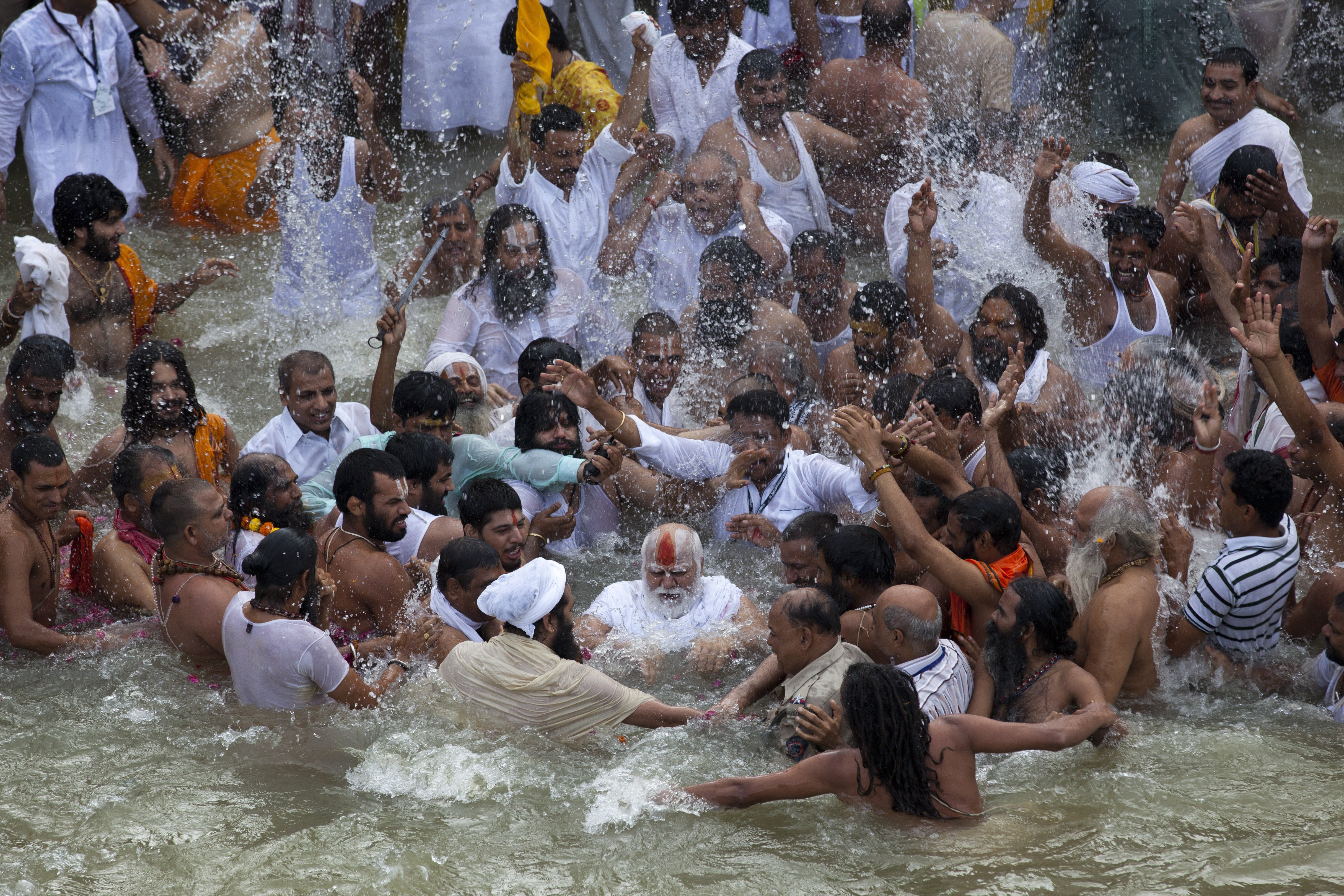 Indian Sadhus, or Hindu holy men, surround their guru, center, during a bath in the Godavari River during Kumbh Mela, or Pitcher Festival in Nashik, India, on Aug. 29, 2015.
