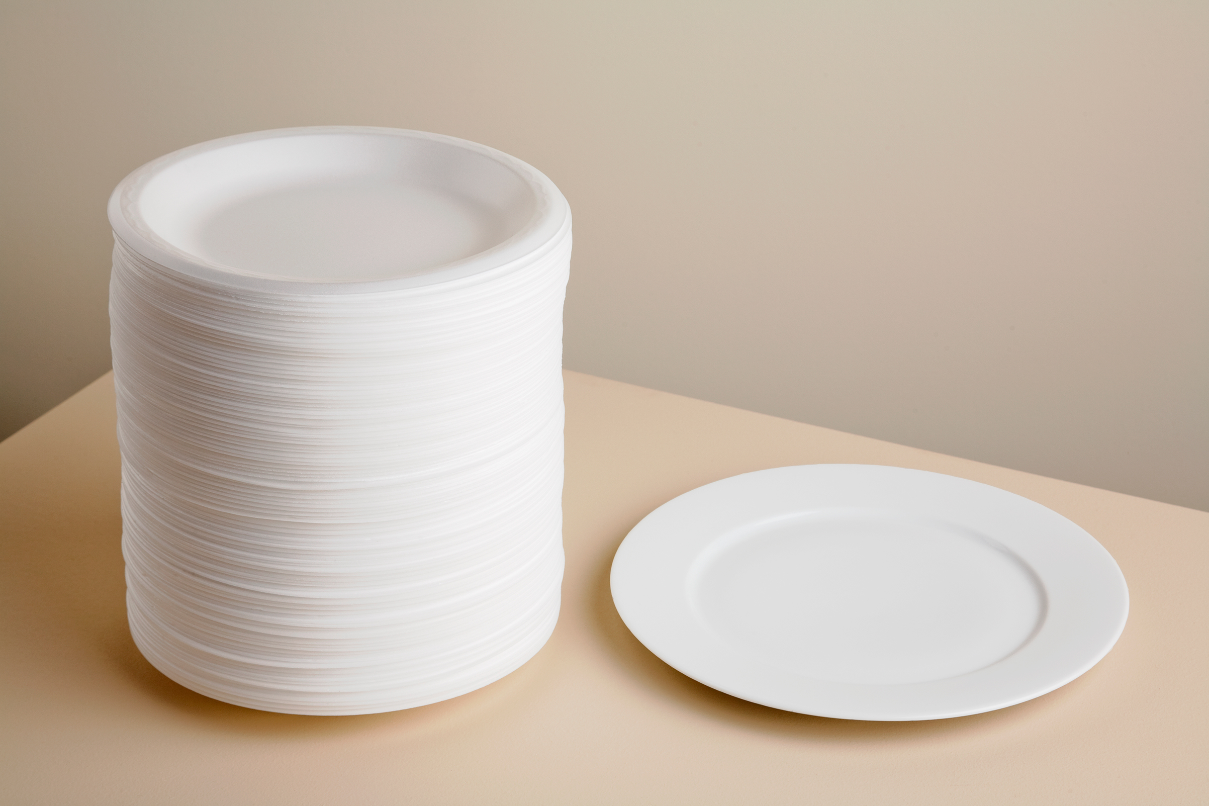 Stack of styrofoam plates and ceramic plate on table