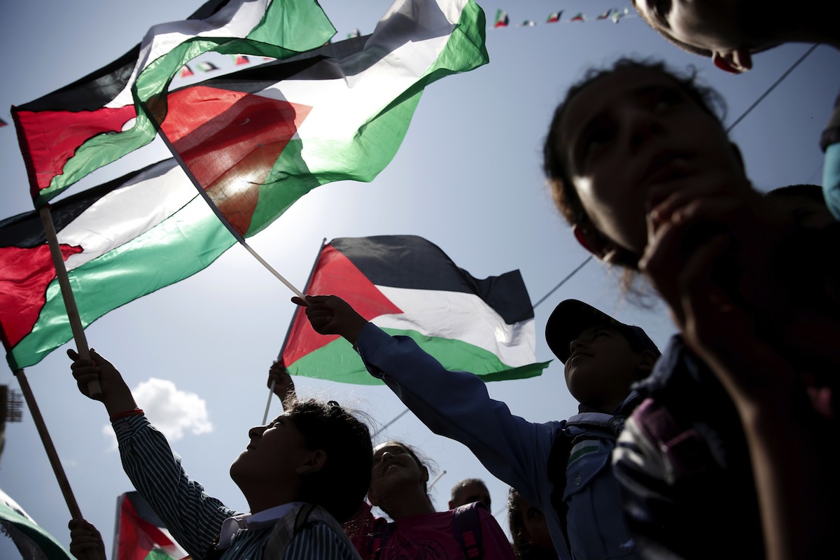 Palestinians wave their flags as they watch a live-screening of president Mahmud Abbas' speech followed by the raising of the Palestinian flag at the United Nations headquarters in New York City, on Sept. 30, 2015 in the city of Ramallah. (Abbas Momani—AFP/Getty Images)