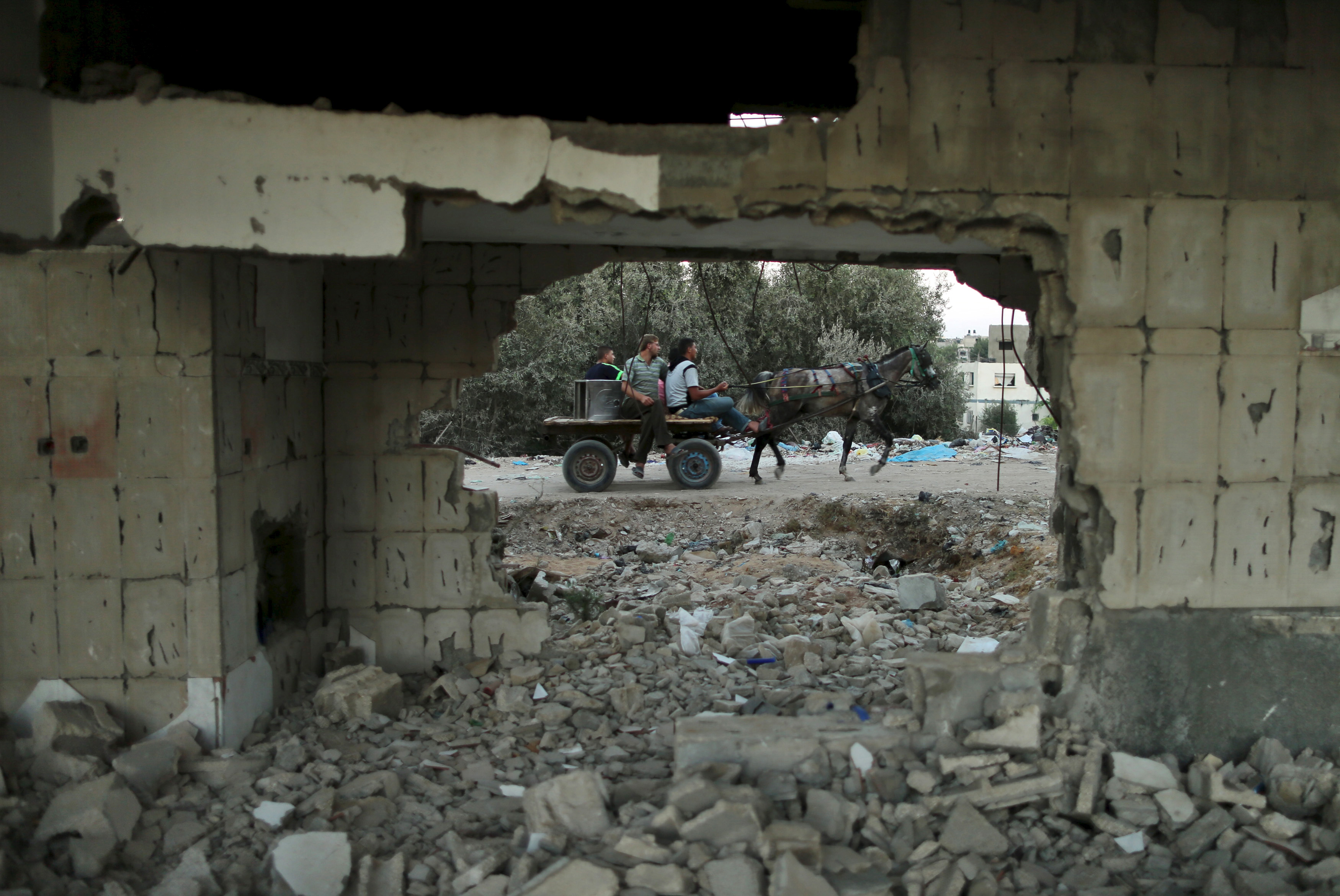 Palestinians ride a horse cart past a house, that witnesses said was destroyed by Israeli shelling during a 50-day war last summer, in Beit Lahiya town in the northern Gaza Strip on Aug. 25, 2015. (Mohammed Salem—Reuters)