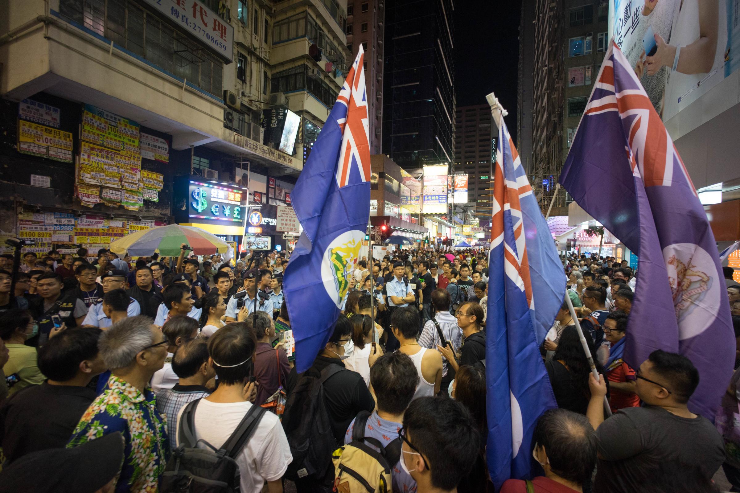 MONG KOK, HONG KONG - 2015/08/02: Pro democracy localists seen waving the British colonial flag as they protest against the pro Beijing street performers. Police force was deployed to protect the Pro Beijing street performers on their meeting with the Pro Democracy local protesters in the shopping district of Mong Kok. (Photo by Geovien So/Pacific Press/LightRocket via Getty Images)