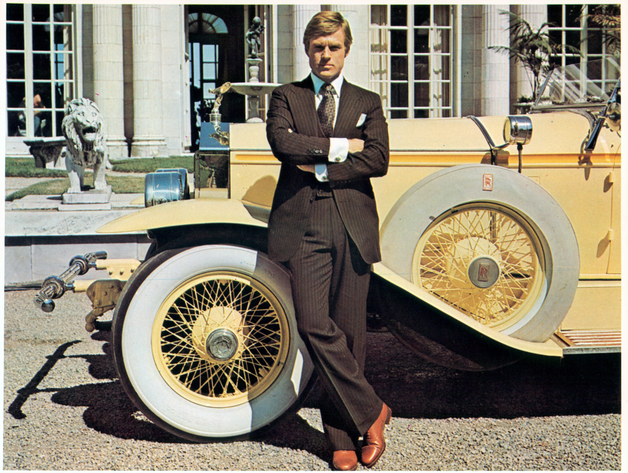 Robert Redford, wearing a Ralph Lauren suit, leaning against luxurious car in a scene from the film The Great Gatsby, 1974.