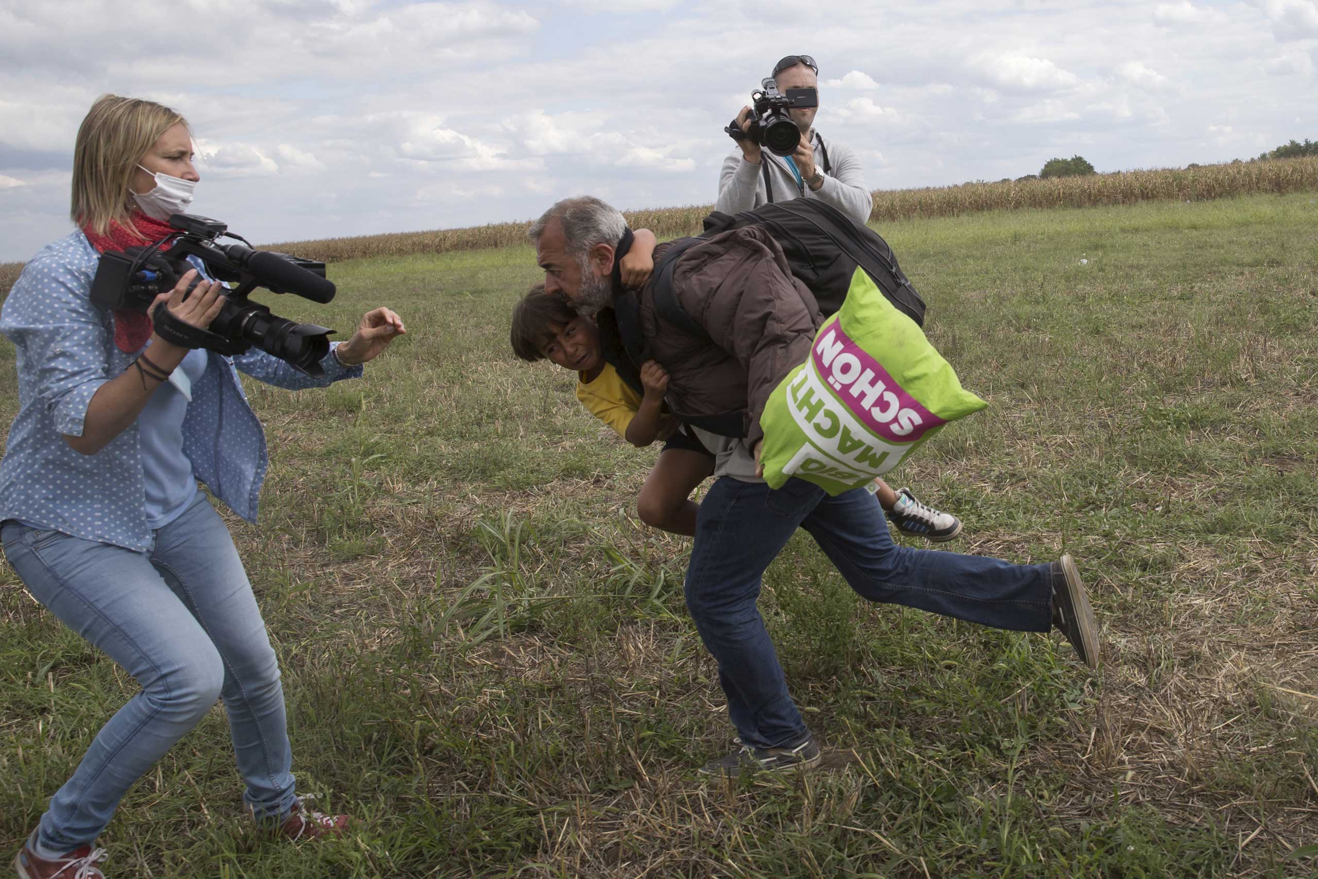 A migrant runs with a child before tripping on TV camerawoman Petra Laszlo (L) and falling as he tries to escape from a collection point in Roszke village, Hungary, Sept. 8, 2015 (Marko Djurica—Reuters)