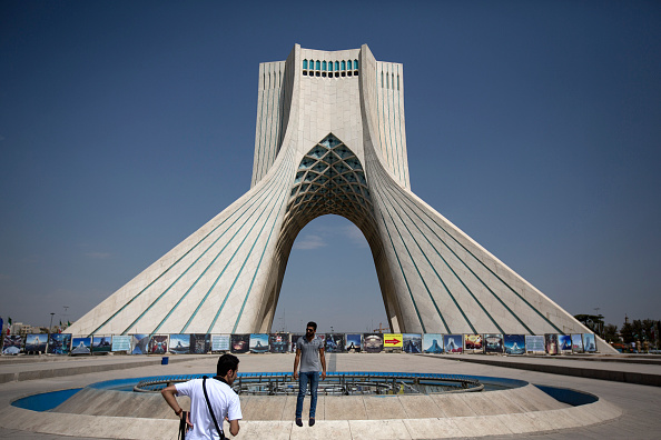 An Iranian tourist poses for a photograph in front of the Azadi tower in Tehran, Iran, on Friday, Aug. 21, 2015.
