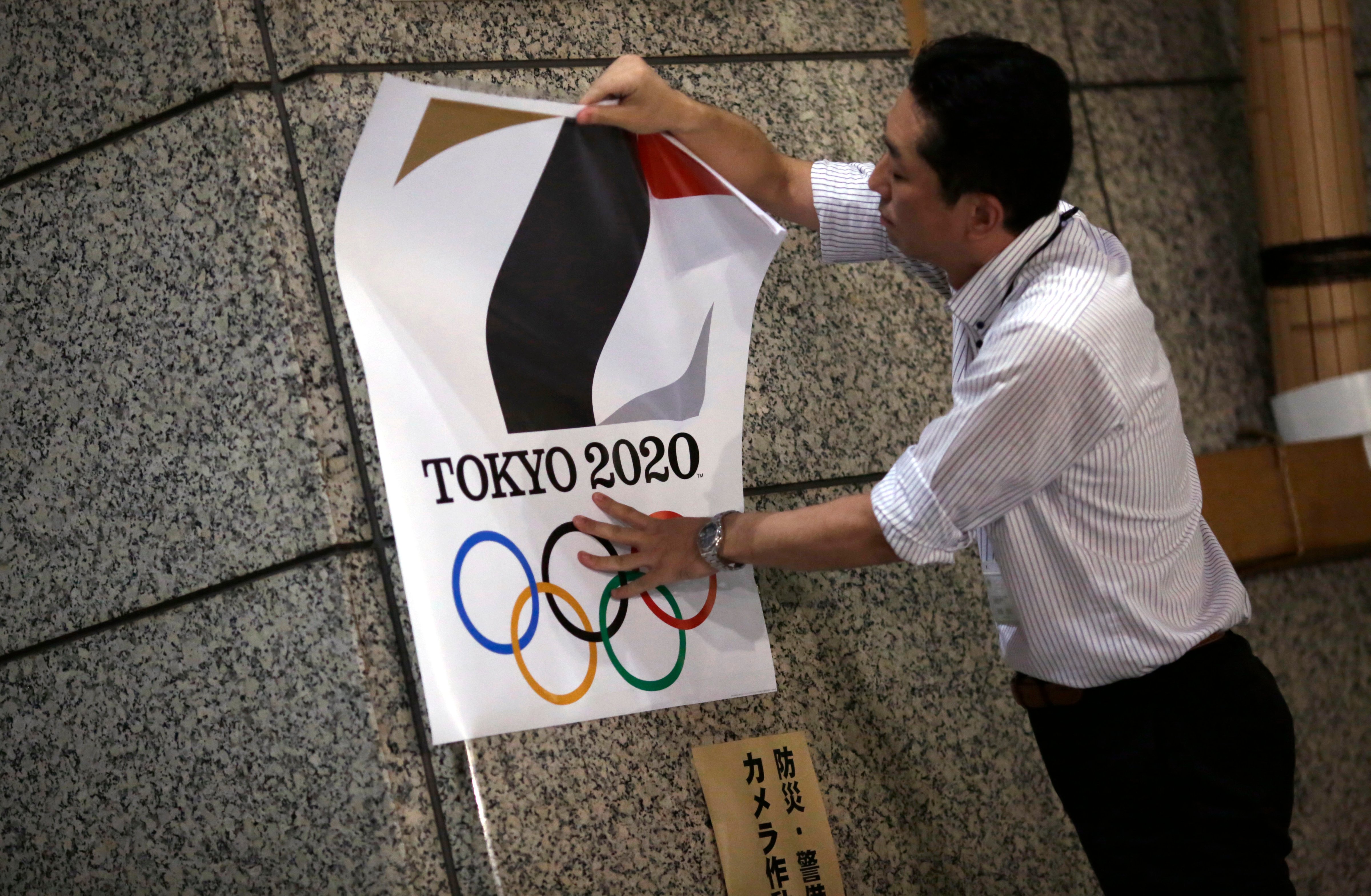 The poster with a logo of Tokyo Olympic Games 2020 is removed from the wall by a worker during an event staged for photographers at the Tokyo Metropolitan Government building in Tokyo Tuesday, Sept. 1, 2015 (Eugene Hoshiko—AP)