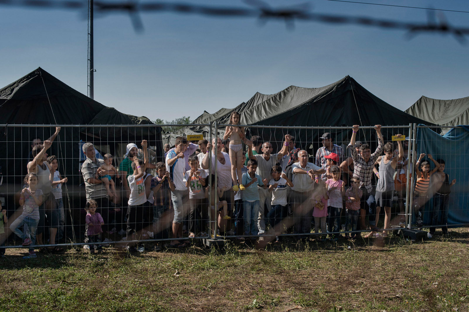 A group of migrants waits at a makeshift detention camp for Hungarian authorities to register their arrival in the European Union.
                      Roszke, Hungary, Aug. 29, 2015. (Yuri Kozyrev—NOOR for TIME)