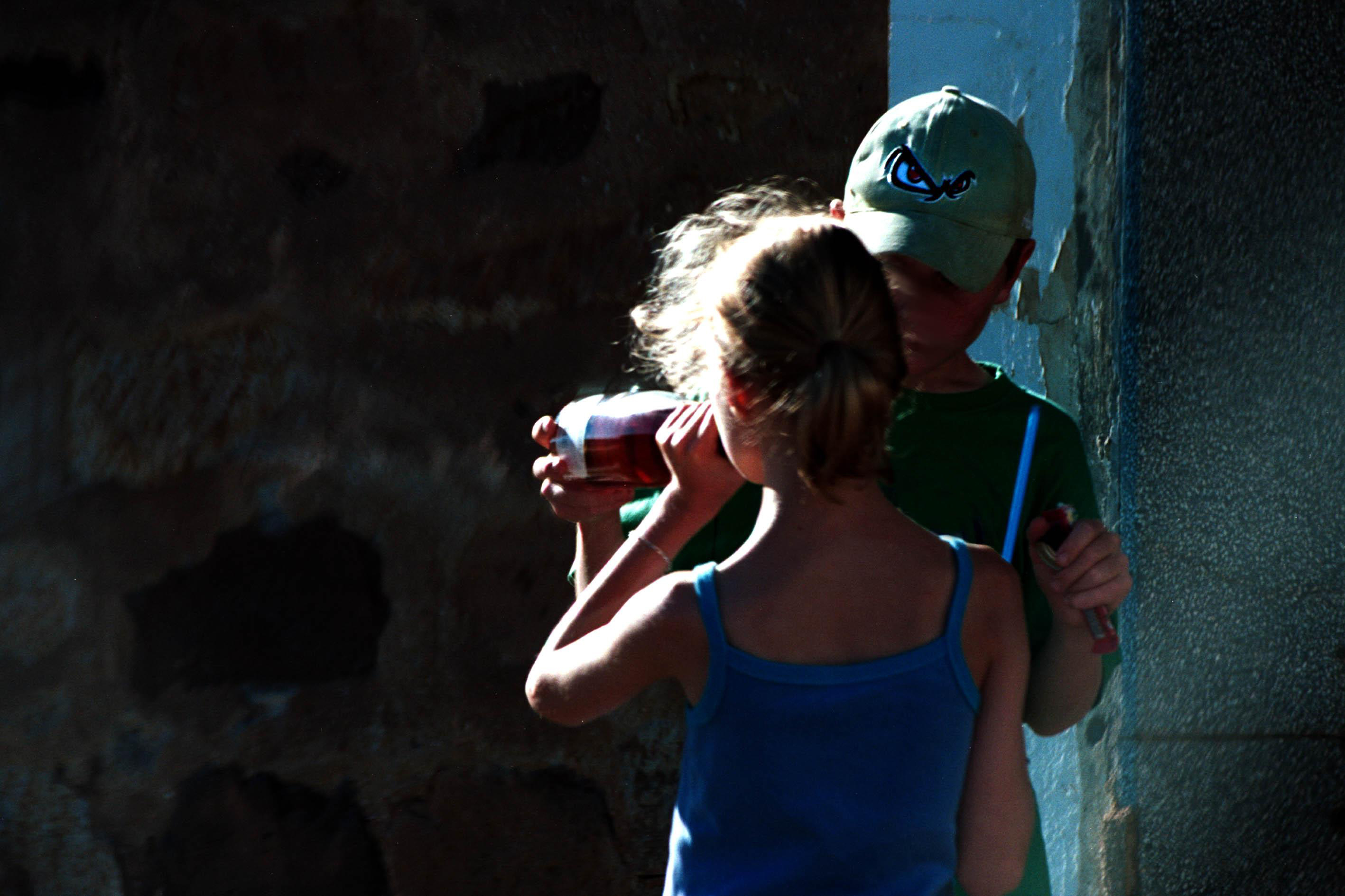 Young boy giving a bottle of wine to a young girl