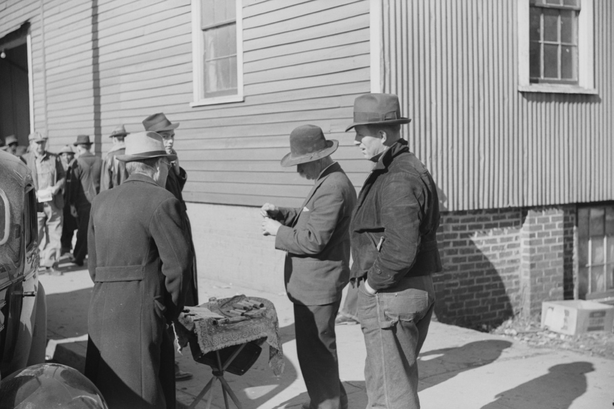 Salesman displaying patent medicine to farmers who have brought tobacco to warehouse and are waiting outside for the sales to begin. Mebane, N.C., 1939. (Universal History Archive /  Getty Images)