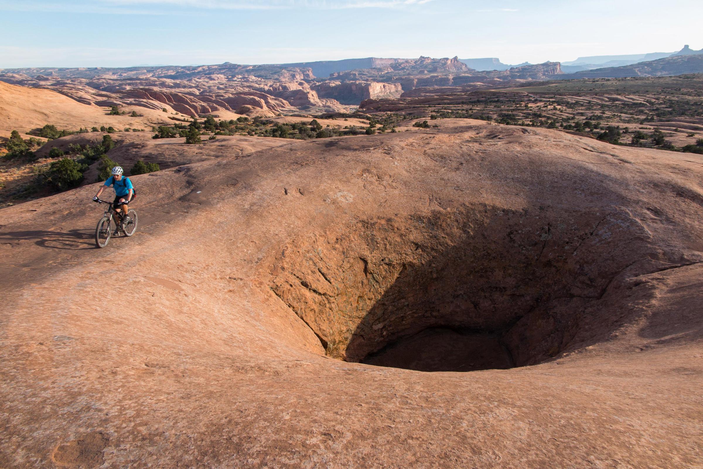04 Apr 2015, Moab, Utah, USA --- Apr 5, 2015 - Moab, Utah, U.S. - Mountain biker TIM LANE rides past a giant wind blown bore hole in the rock on the red slickrock sandstone of Poison Spider trail. The Poison Spider Mesa trail is one of the ''Must Do'' rides of Moab. Combining physically demanding biking challenges with great views, this trail is for expert bikers. The trail can be ridden as an out-and-back, or a 13-mile loop that includes the infamous Portal Trail as the return-route off the mesa. (Credit Image: ¬© Ruaridh Stewart/ZUMA Wire/ZUMA Press) --- Image by © Ruaridh Stewart/ZUMA Press/Corbis