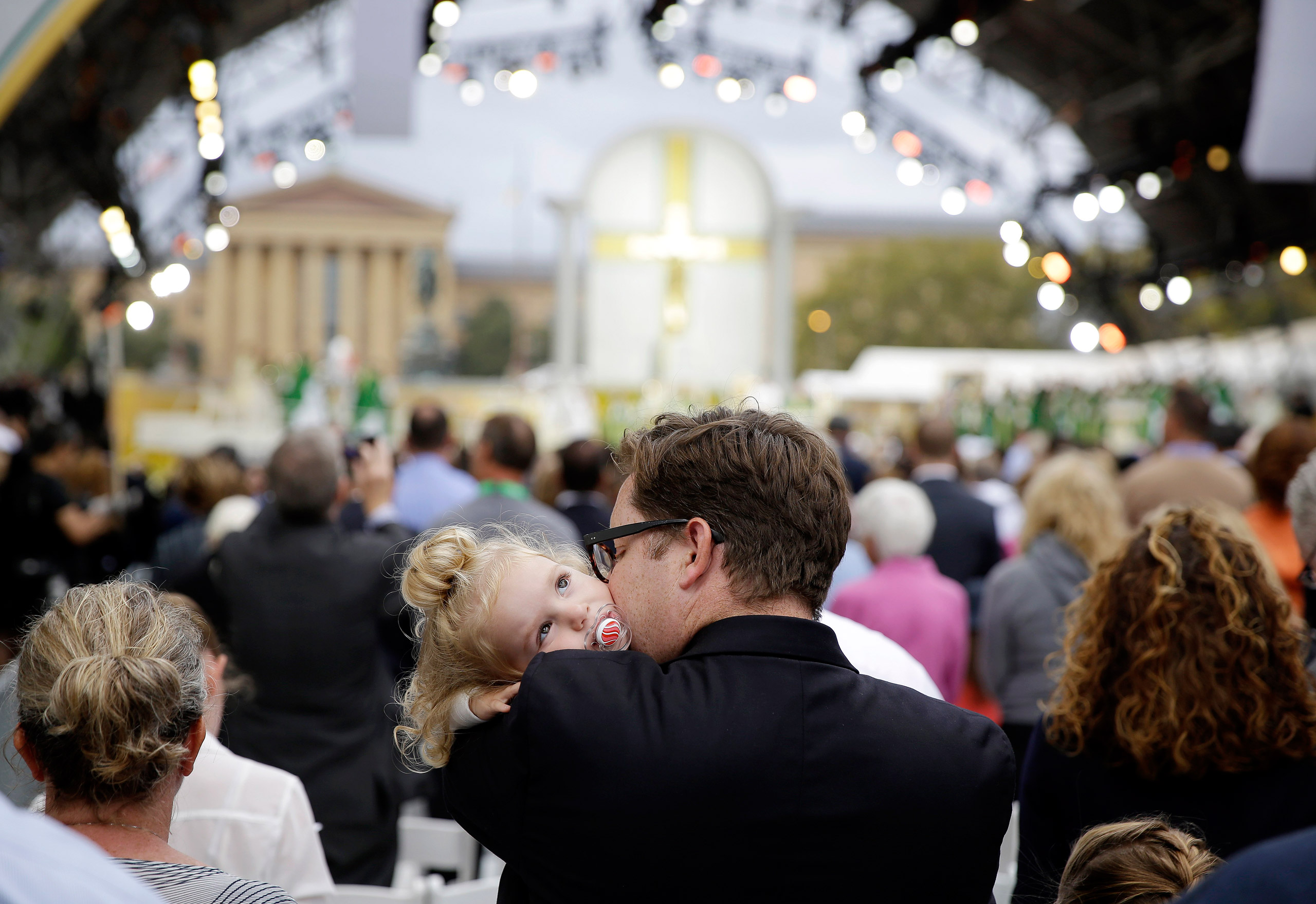 A man holds a child as Pope Francis celebrates mass in Philadelphia on Sept. 27, 2015.