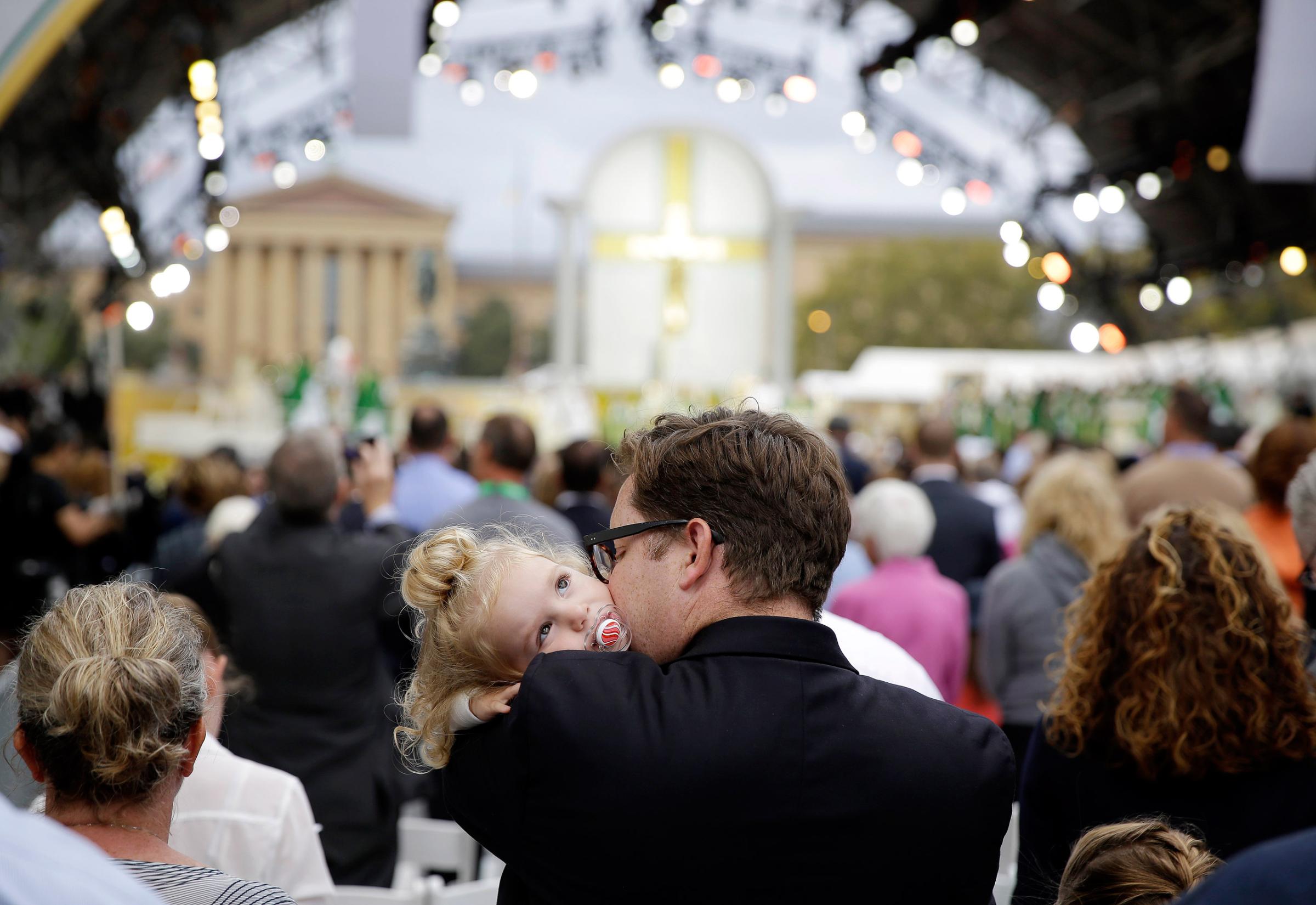 A man holds a child as Pope Francis celebrates Mass, Sunday, Sept. 27, 2015, in Philadelphia. (AP Photo/Matt Slocum)