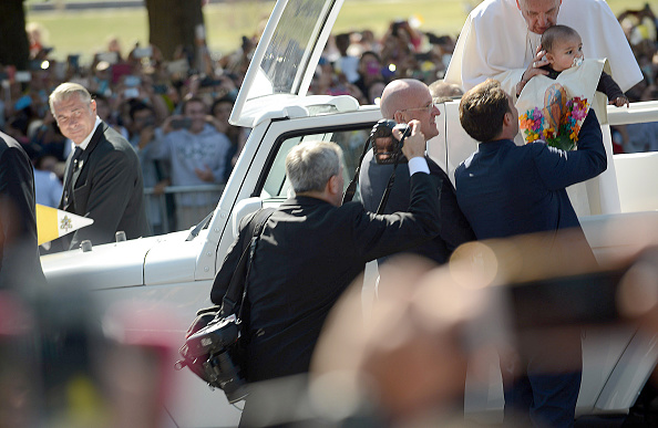 Pope Francis blesses a child handed to him during a parade on the streets around the Ellipse, south of the White House, September 23, 2015 in Washington, DC.