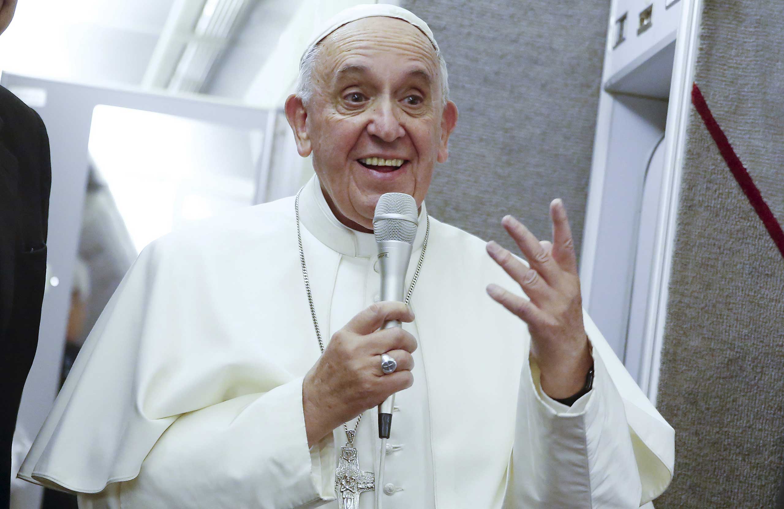 Pope Francis talks aboard the papal plane while en route to Italy