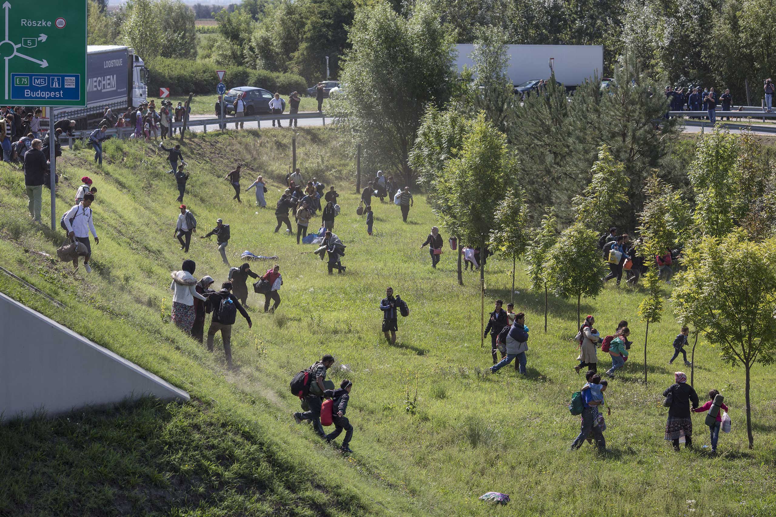 Migrants run over a motorway from a collection point that had been set up to transport people to camps in Morahalom, Hungary, on Sept. 9, 2015.