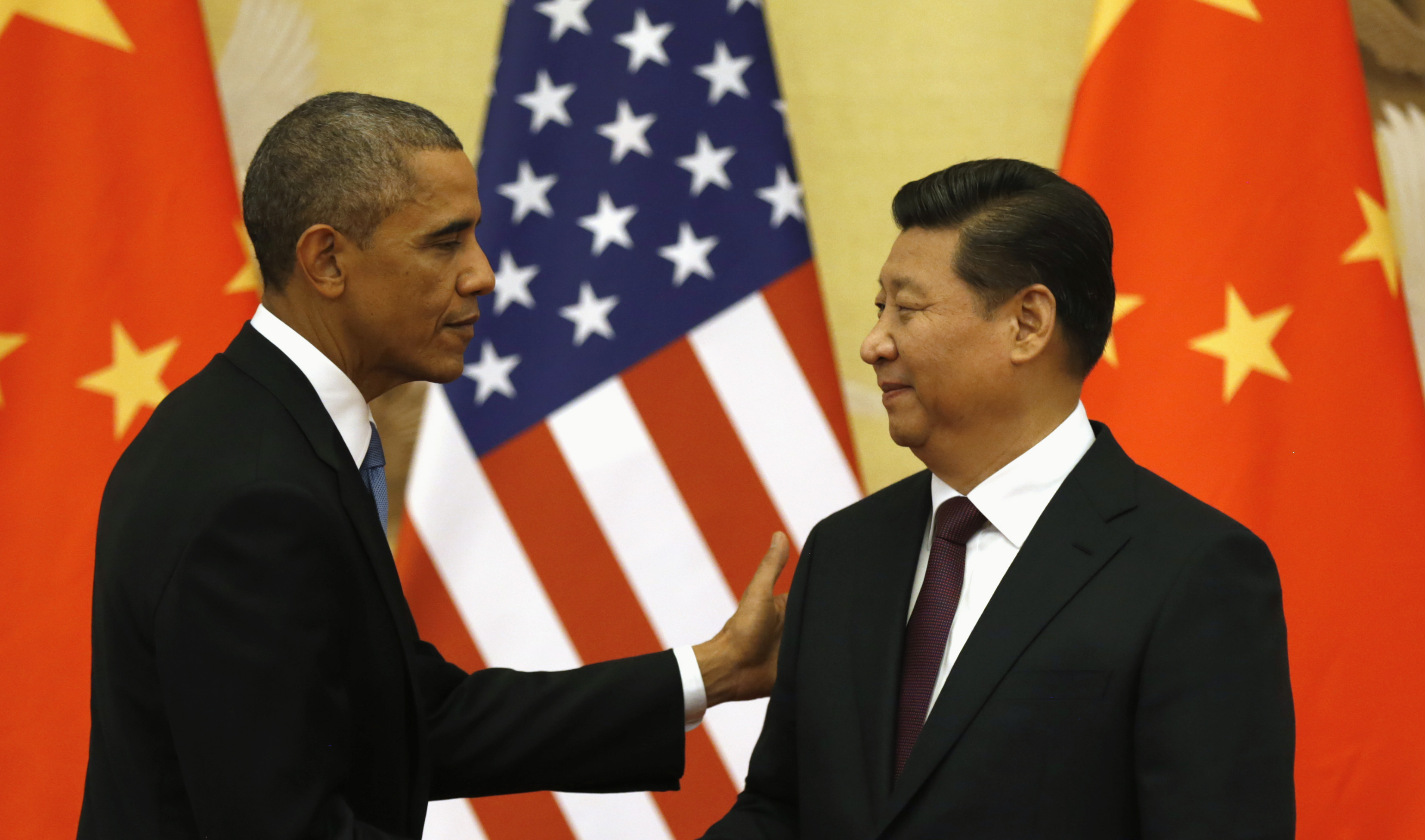 Obama pats Xi on the shoulder at the end of their news conference in the Great Hall of the People in Beijing