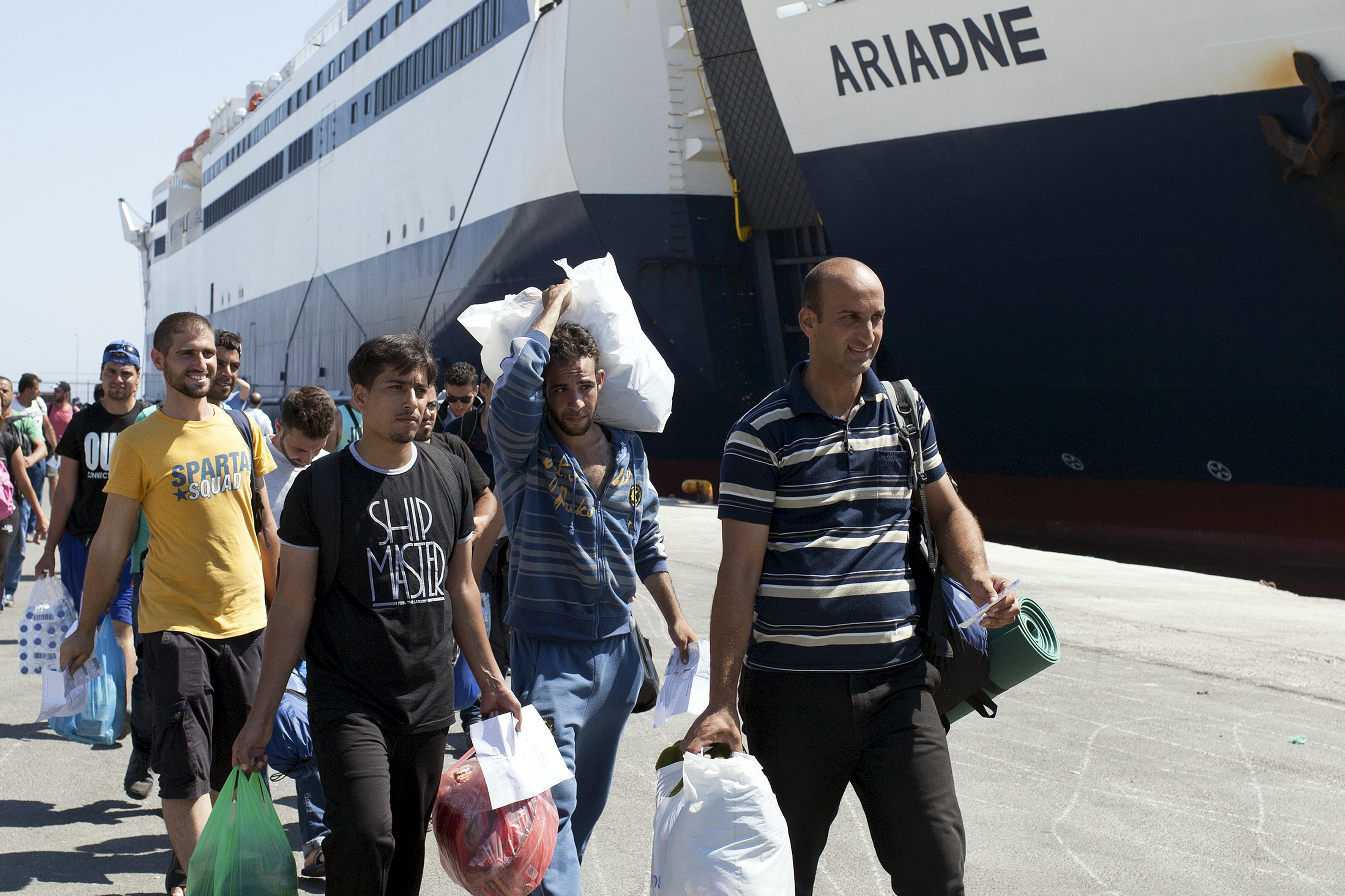 Refugees and migrants carry belongings while boarding passenger ship "Tera Jet" heading to port of Piraeus, at port on island of Lesbos