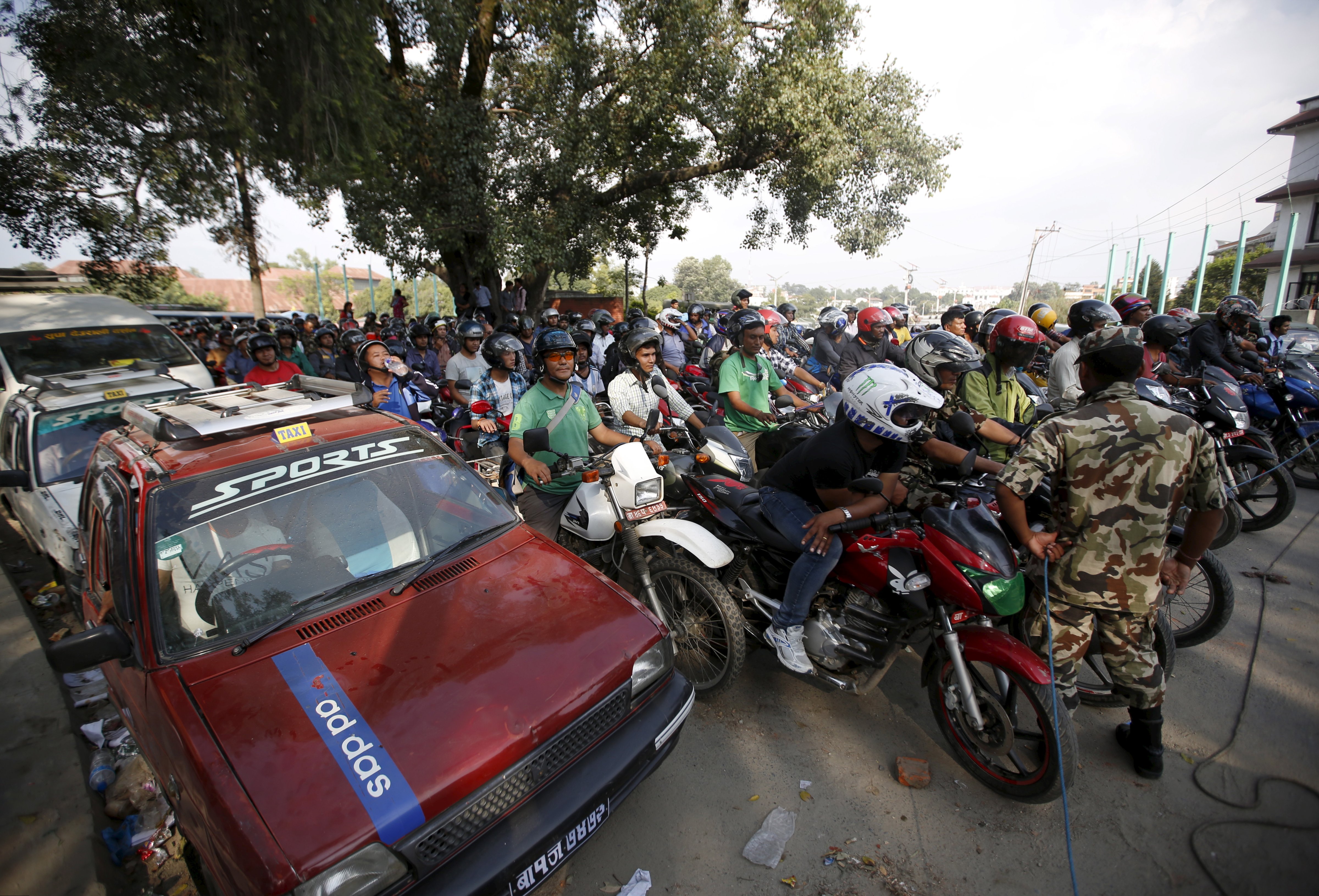 Nepalese people wait in a queue to fill petrol for their vehicle near a petrol station in Kathmandu