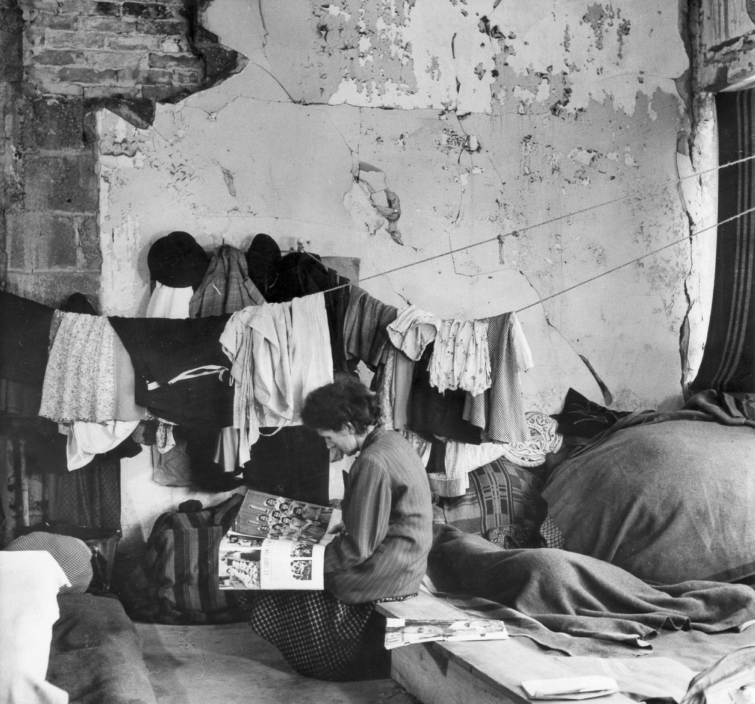 A woman reads a magazine in an emergency accommodation for refugees, around 1945.