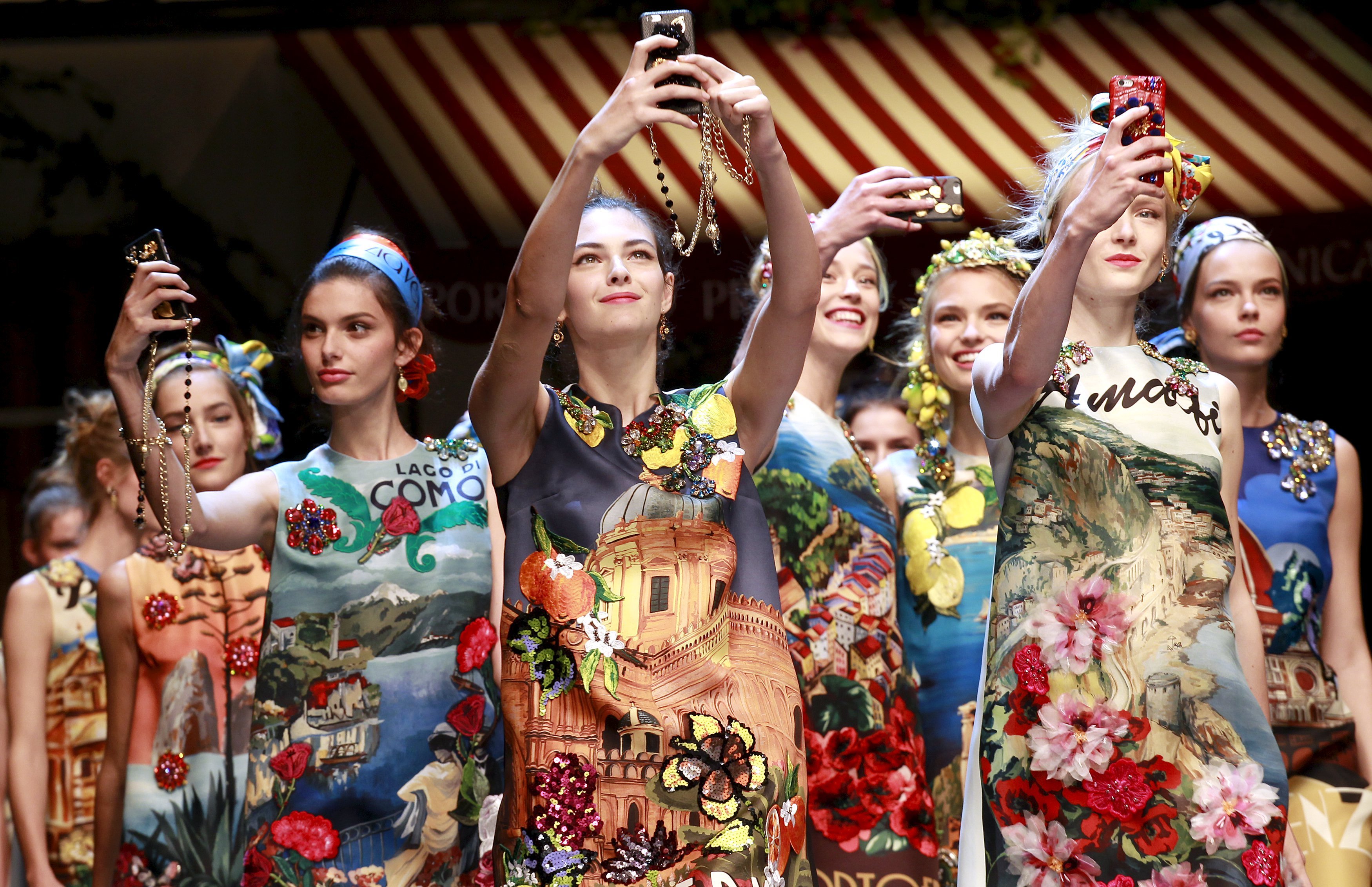 Models take selfie with mobile phones during the parade at the end of the Dolce &amp; Gabbana Spring/Summer 2016 collection during Milan Fashion Week