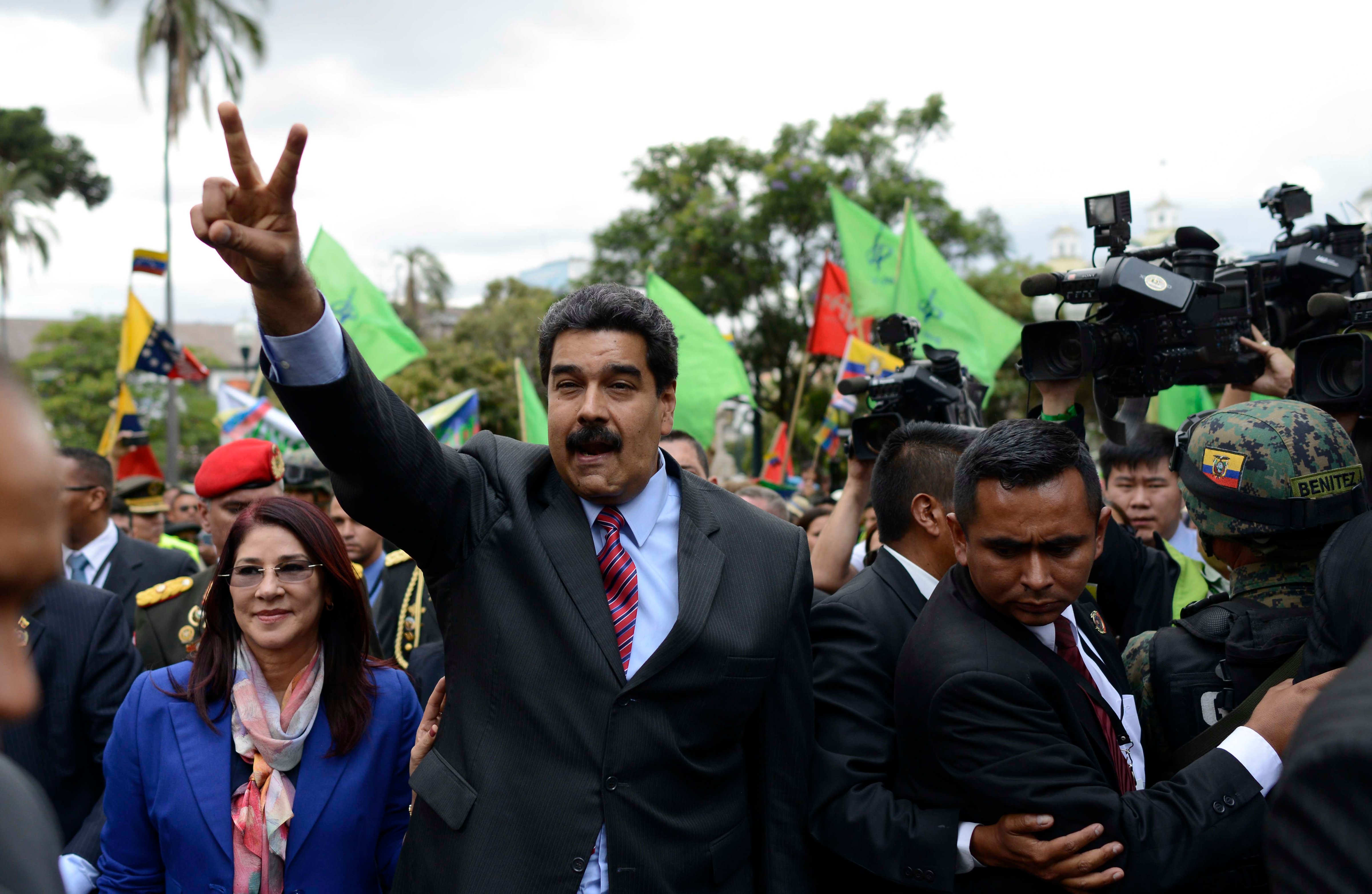 Venezuela's President Nicolas Maduro, accompanied by his first lady Cilia Flores, flashes a peace sign as he arrives at government palace, in Quito, Ecuador, Sept. 21, 2015.