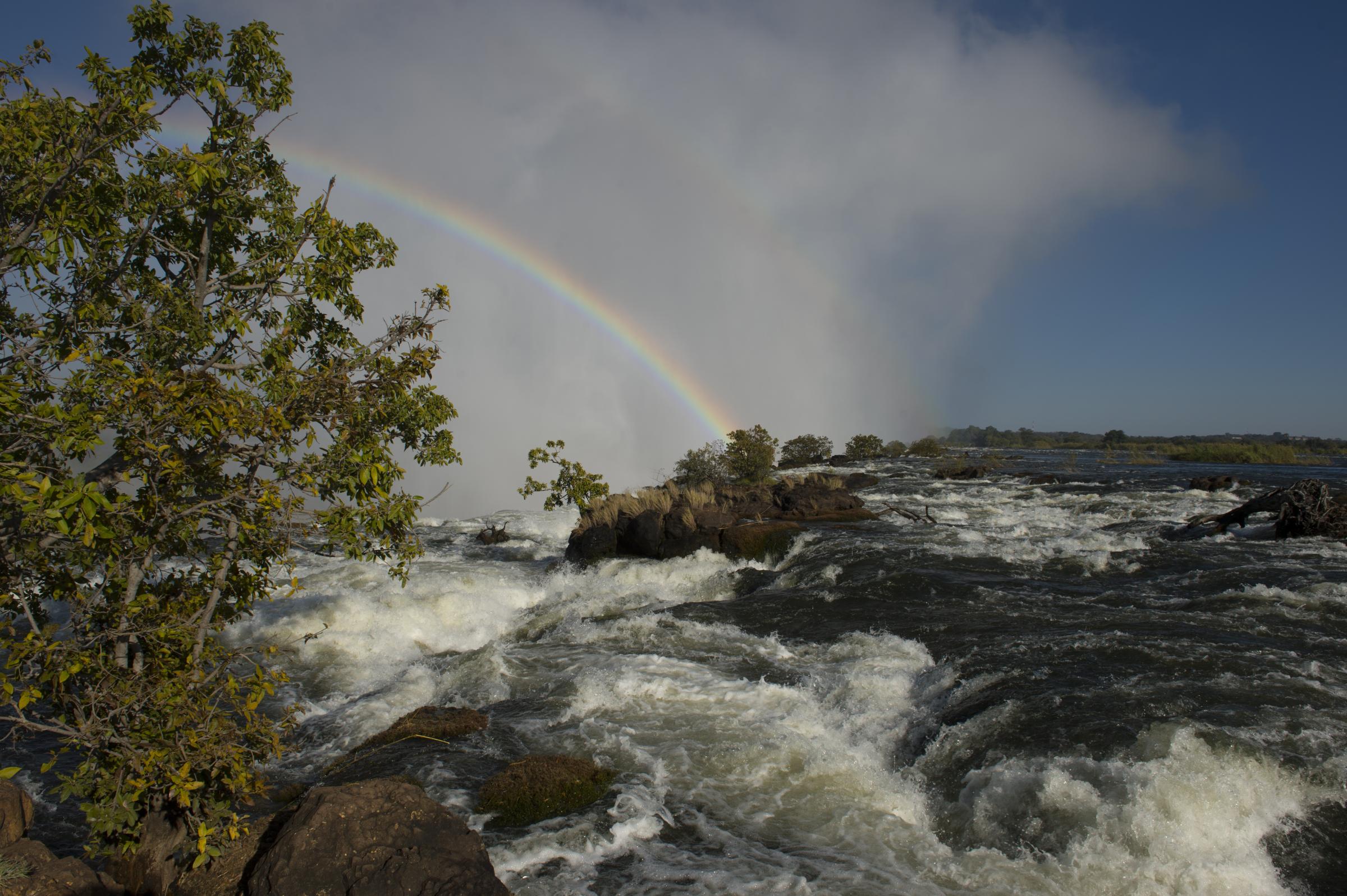 Rainbow over Victoria Falls seen from the shore of the