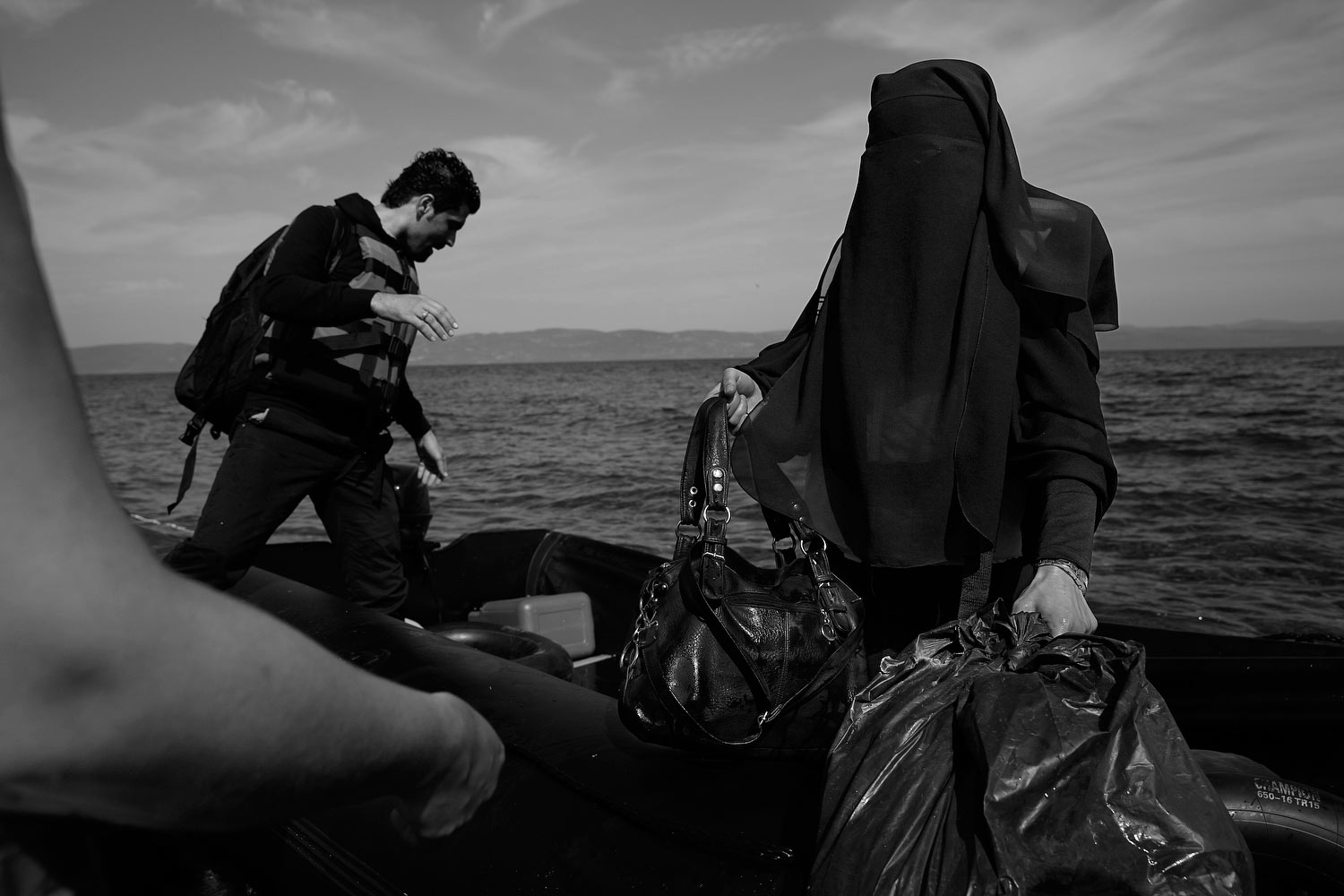 A veiled muslim woman carries both a handbag and garbage bag while getting off an inflatable boat after arriving on the beach in Lesbos, Greece, September 26, 2015. James Nachtwey for TIME
