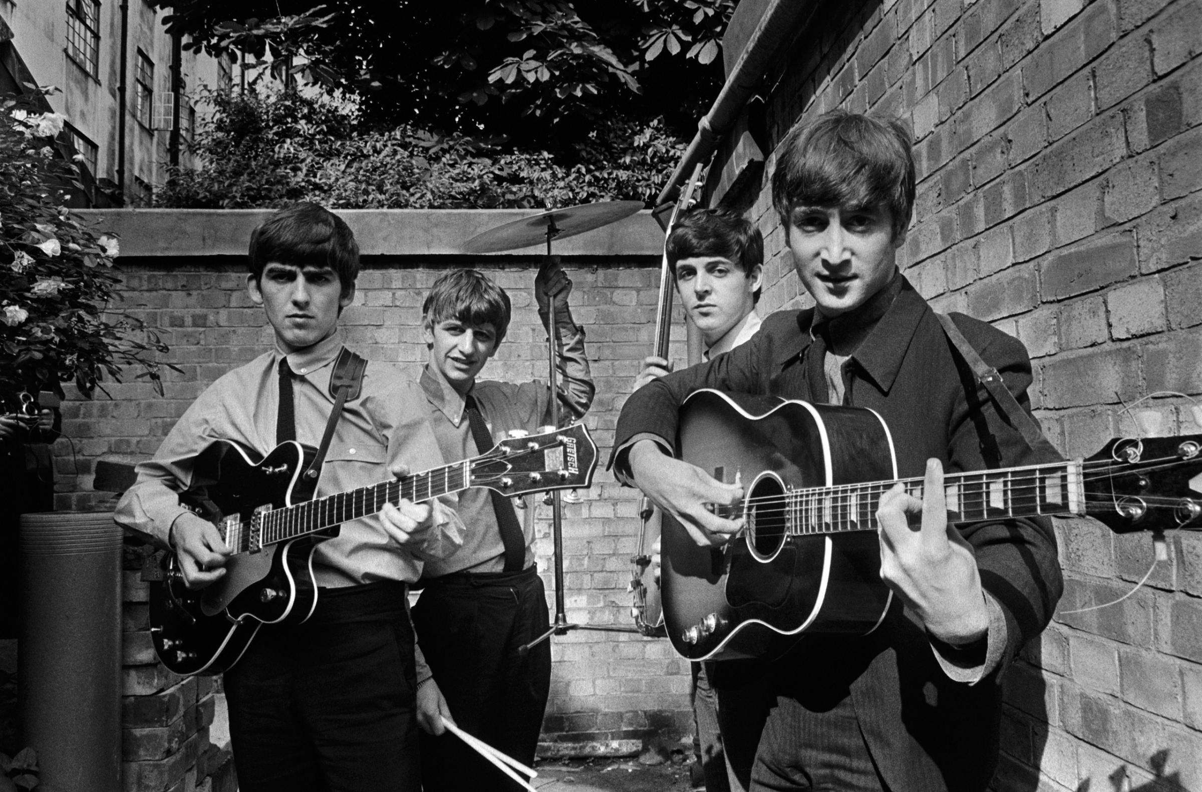 The Beatles posing in a small backyard in London with their instruments, 1963.