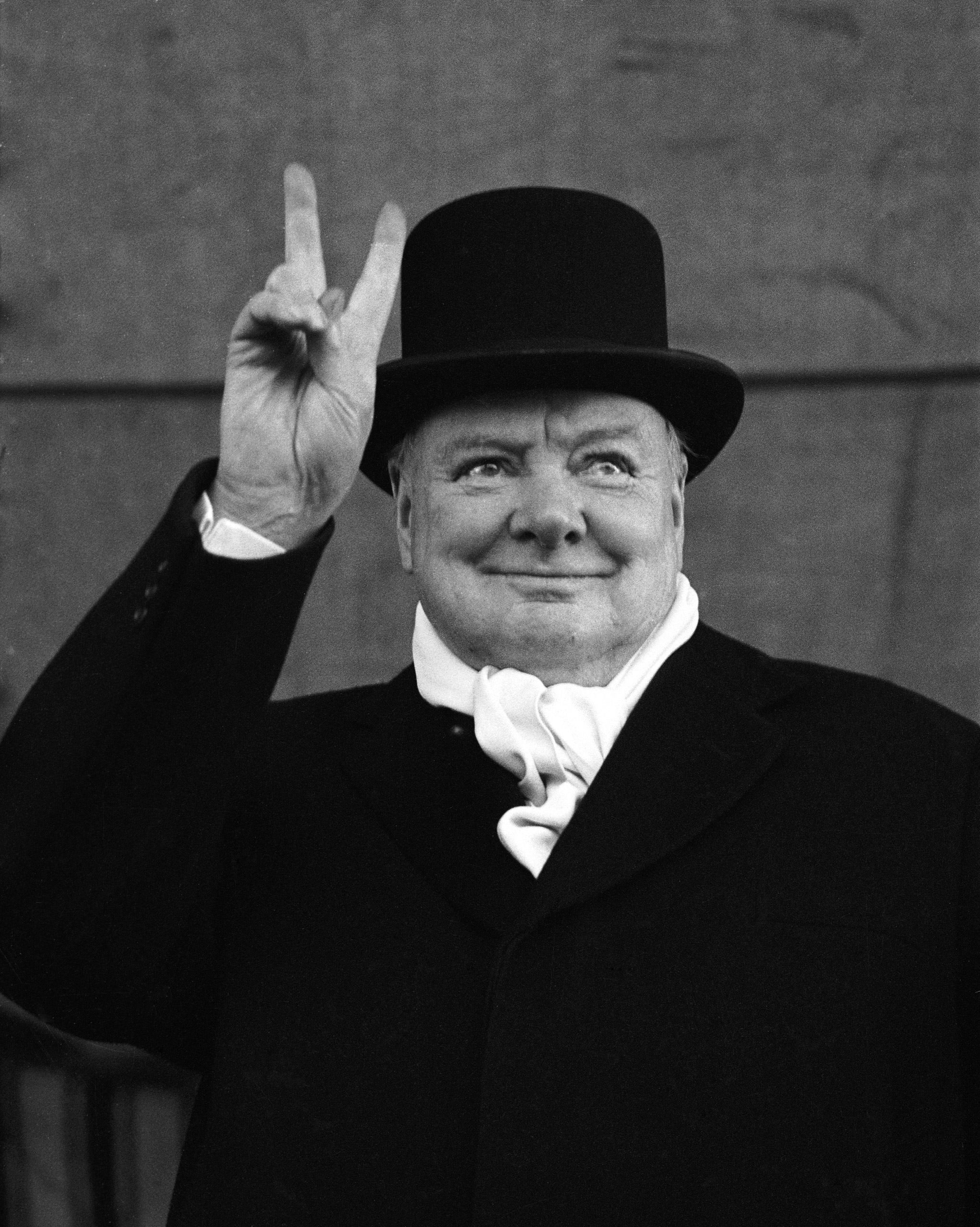 British PM Winston Churchill sporting top hat with coat and scarf.