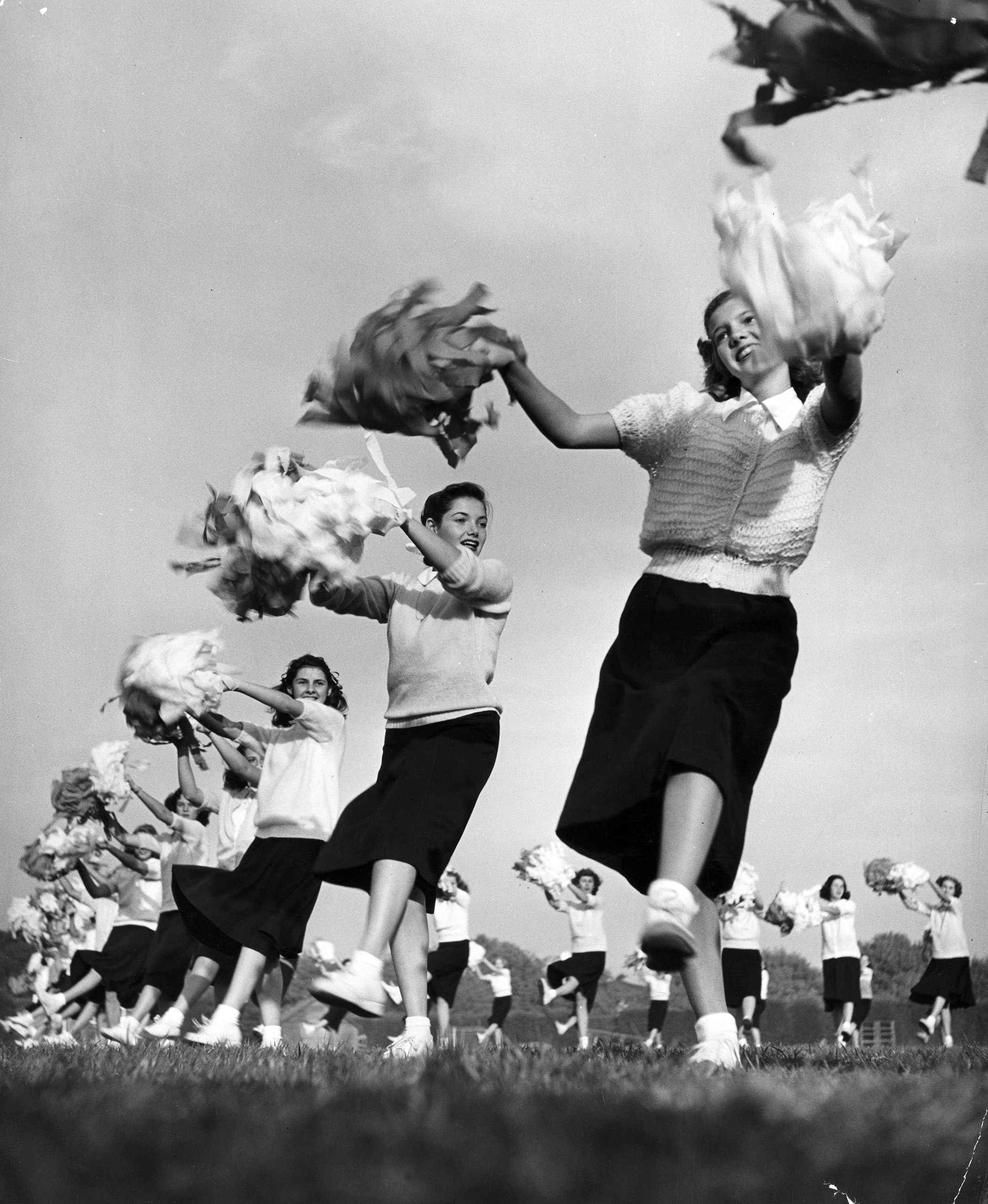 Sixty high school cheerleaders with crepe-paper pompons whip up football spirit, 1947.