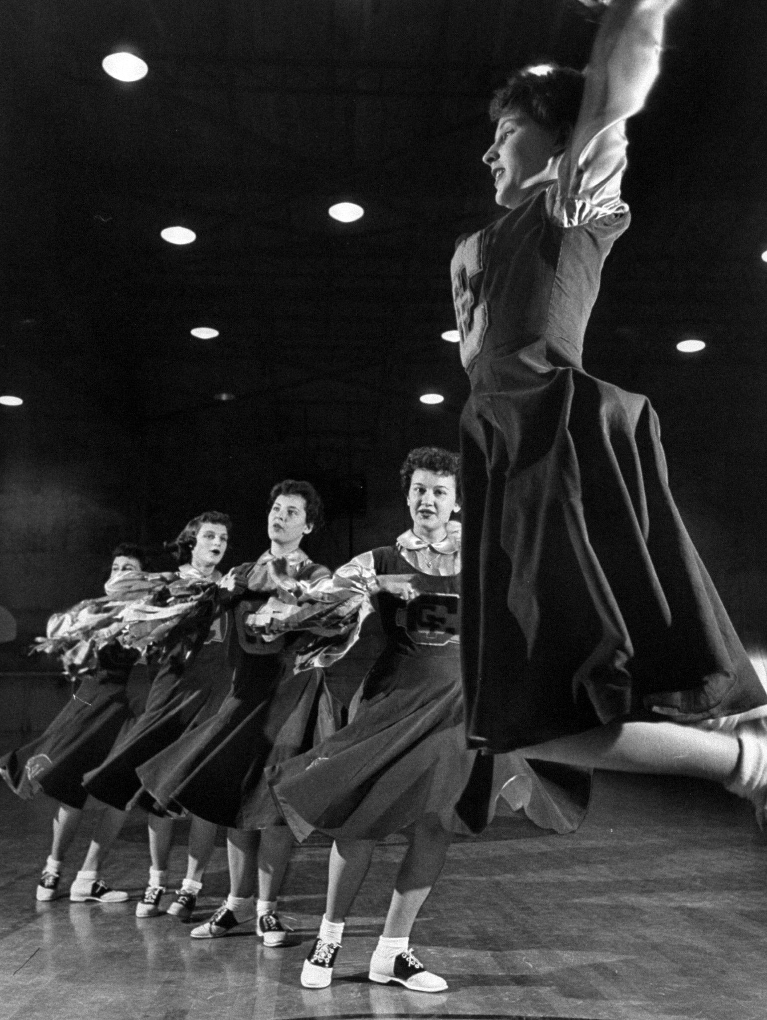 The girls of Central Catholic High School performing their cheerleading act in the gym, 1953.