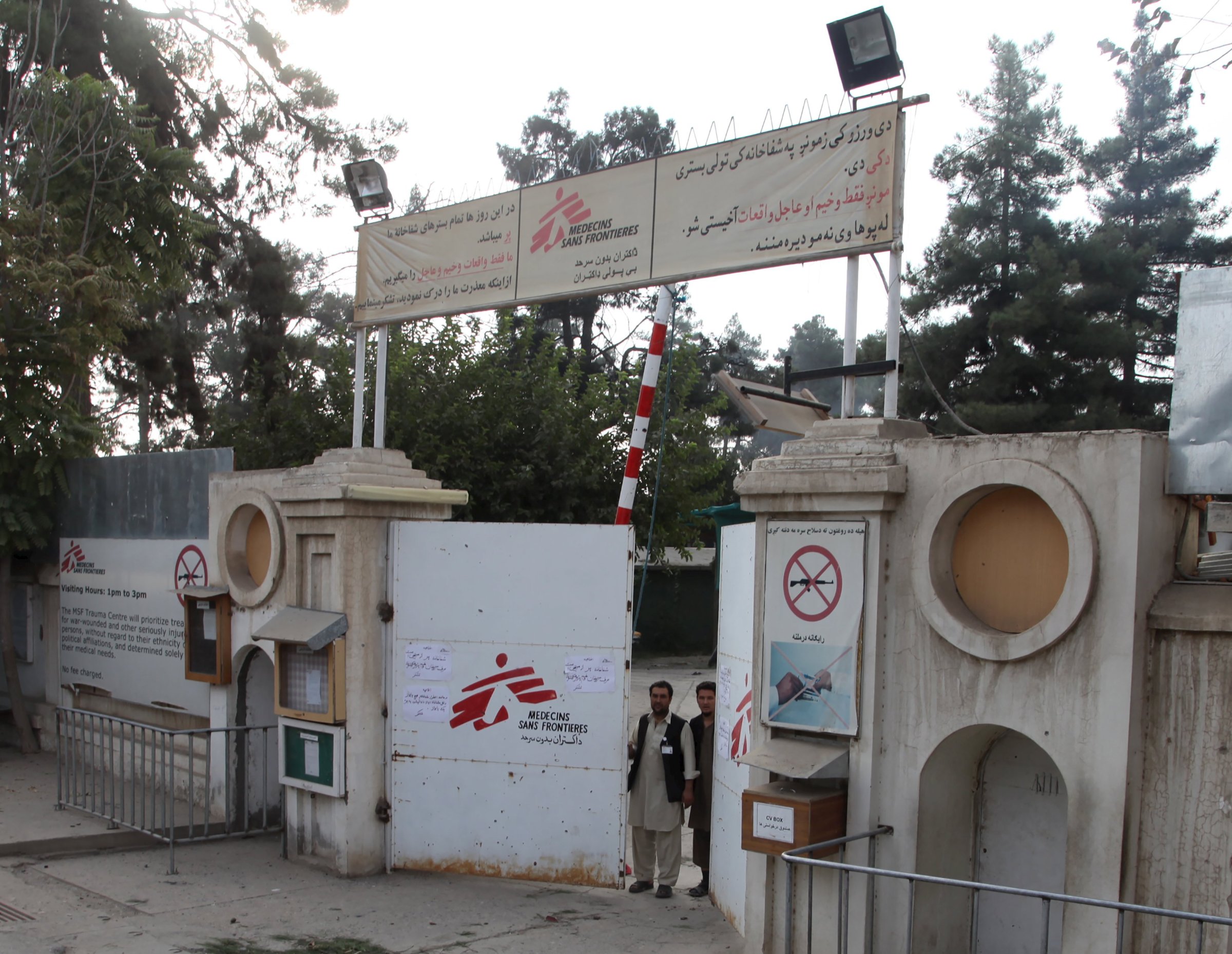 Afghan guards stand at the gate of MSF hospital after an air strike in the city of Kunduz
