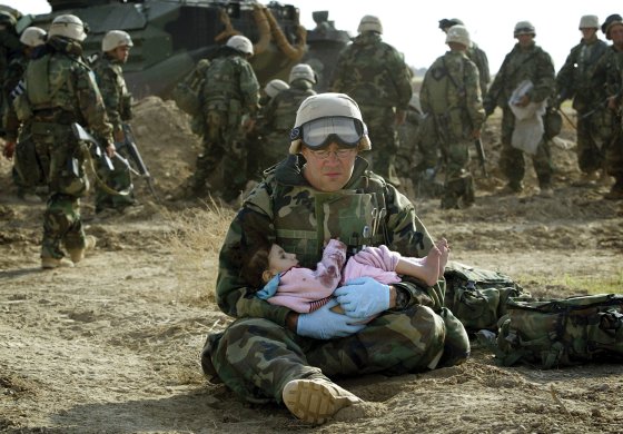 U.S. Marine holds Iraqi child after crossfire ripped apart family in central Iraq