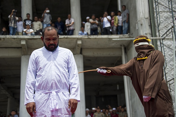 An Indonesian Shari‘a police whips a man during a public caning ceremony outside a mosque in Banda Aceh, capital of Indonesia's Aceh province, on Sept, 18, 2015 (Chaideer Mahyuddin—AFP/Getty Images)