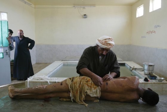 Ali Hadi, a professional body washer, prepares the body of a bombing victim for Muslim burial as the man's relatives watch in Najaf, Iraq.