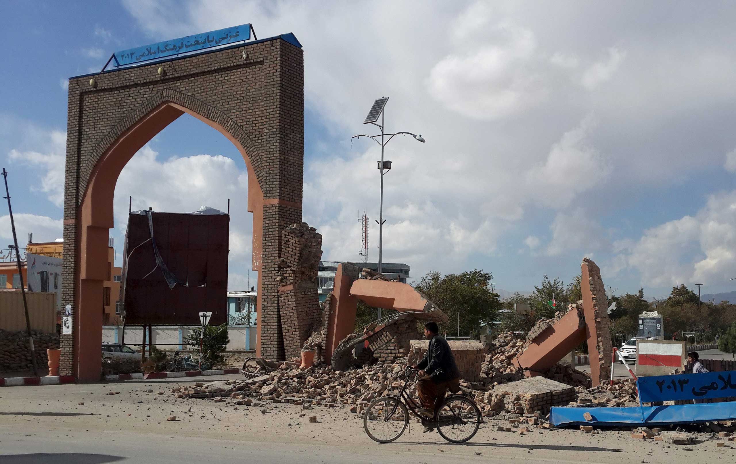 A man rides his bicycle next to damaged structures, after an earthquake in Ghazni, Afghanistan, on Oct. 26, 2015.
