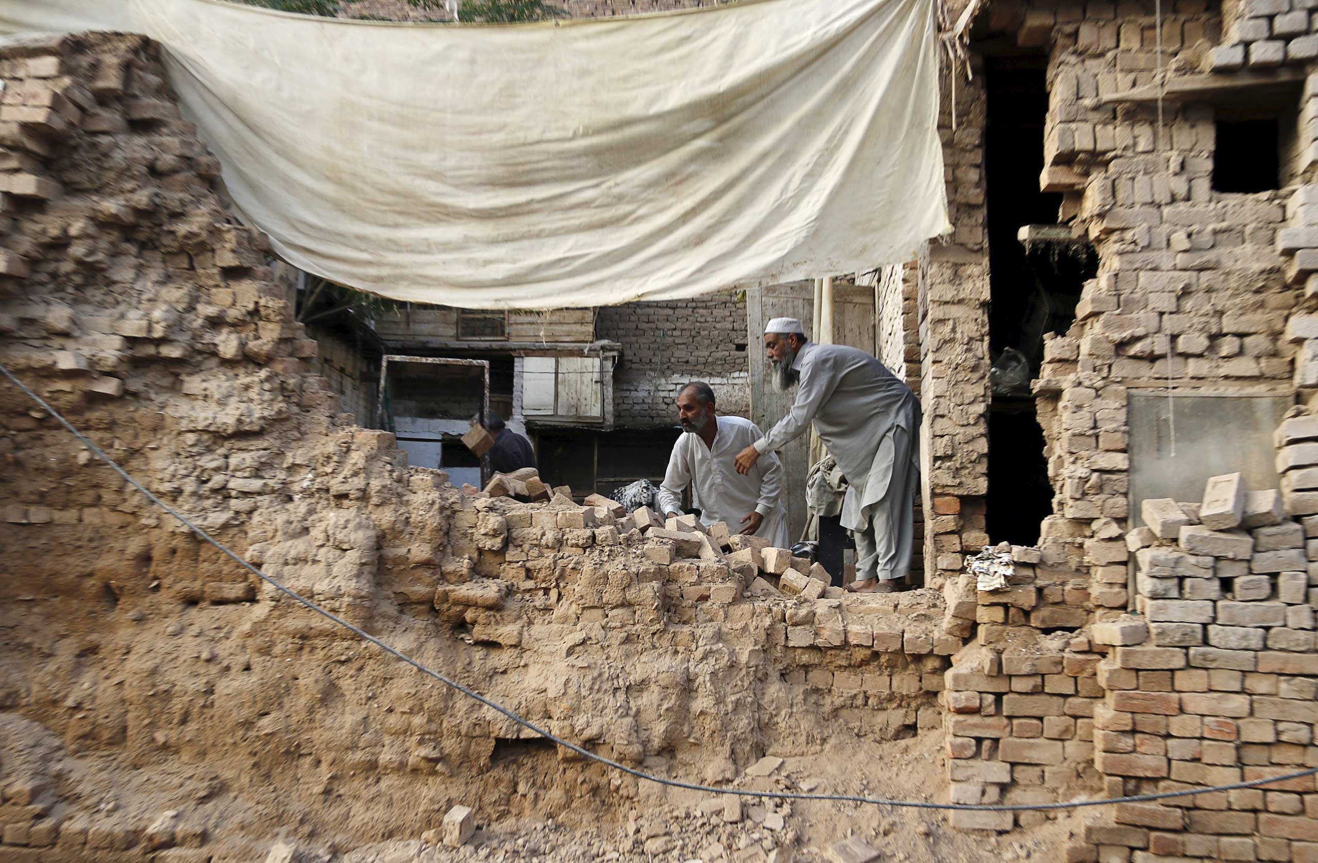 Residents clear the rubble of a house after it was damaged by an earthquake in Peshawar, Pakistan, on Oct. 26, 2015.