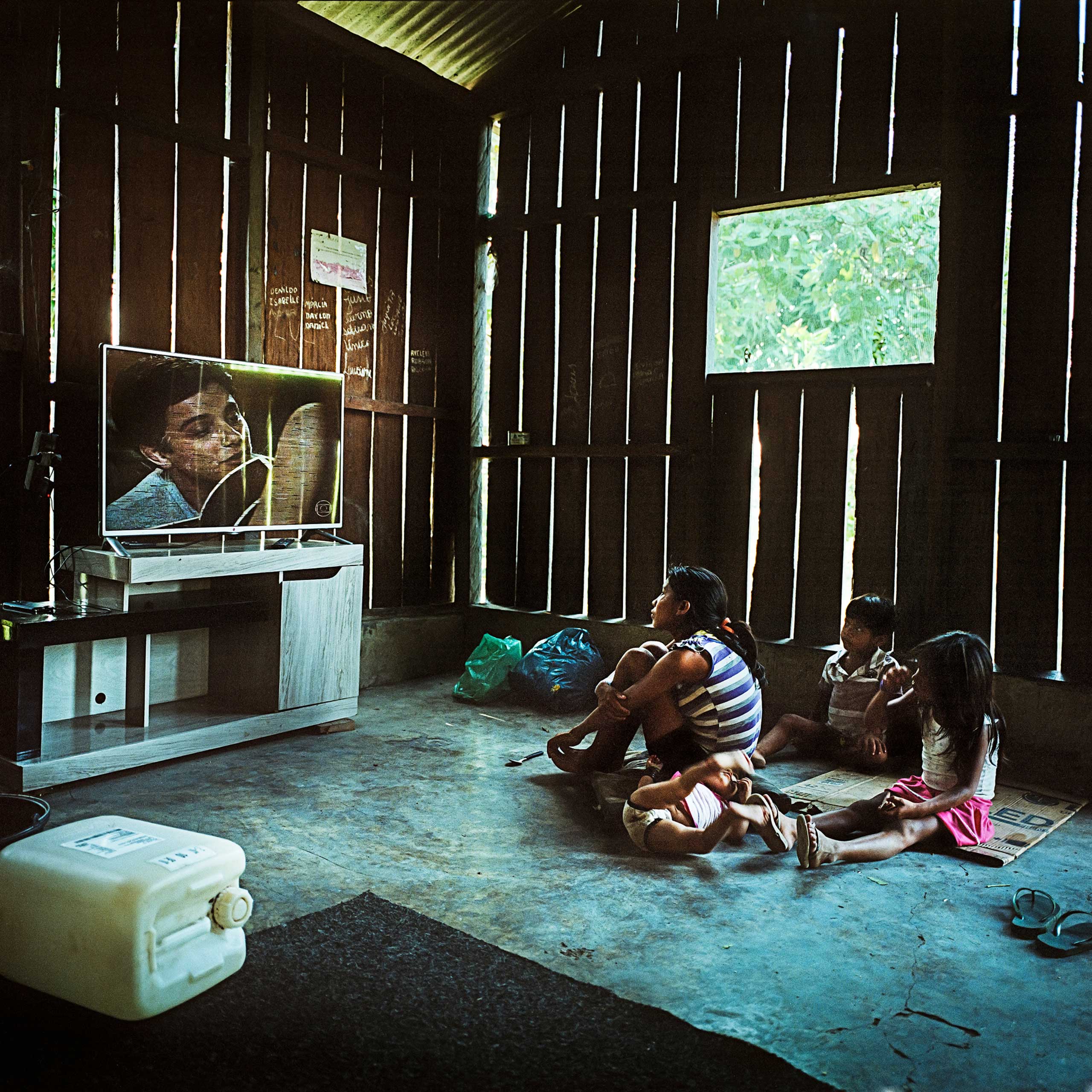A Munduruku family watch Brazilian Soap Operas  in the village of Sawre Muybu. Although living completely off the land their villages have generators, fridges and televisions. Many indigenous communities are provided with these goods by government and industry hoping to win their support for the proposed dams, Dec. 2014.