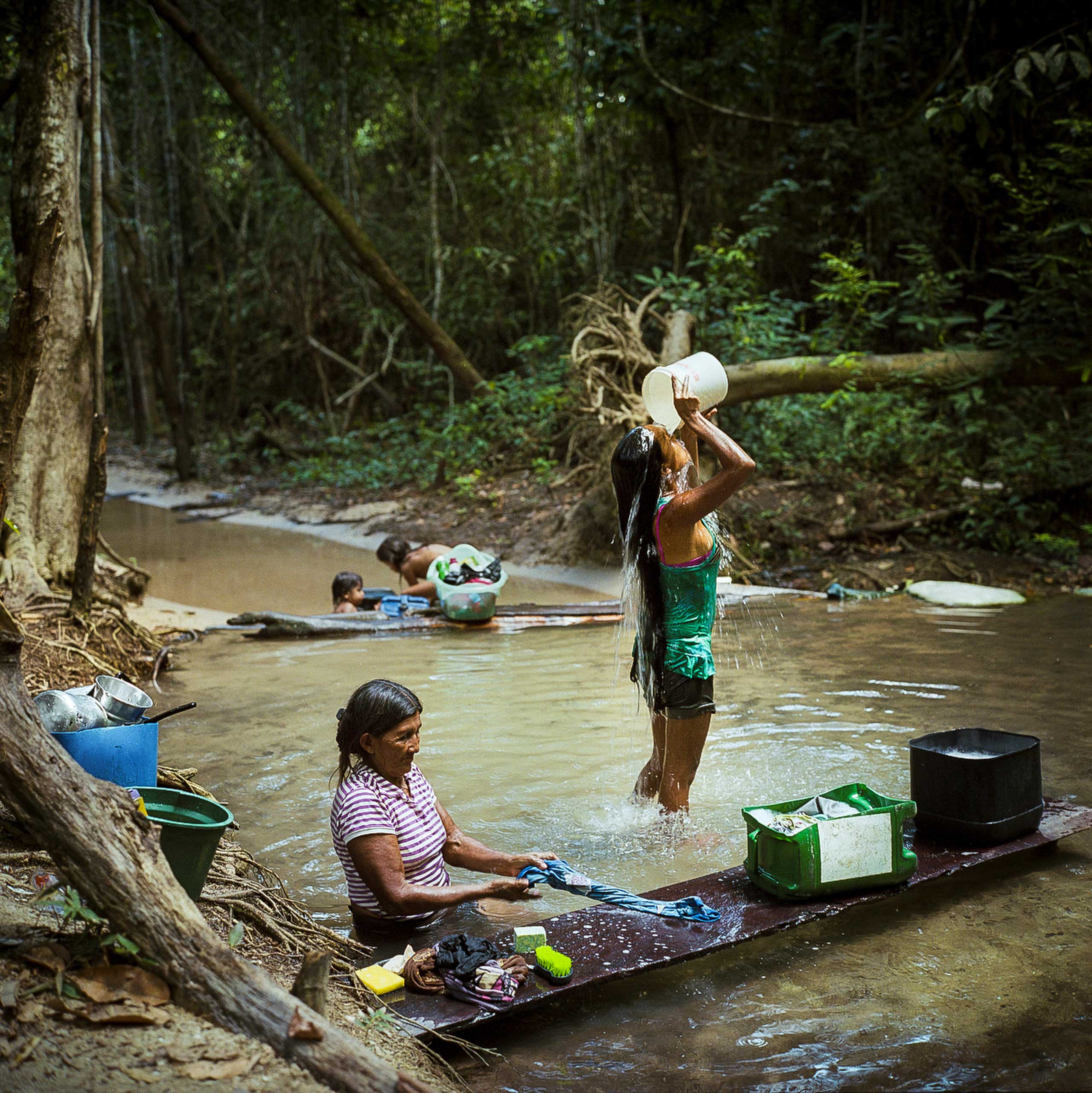 Munduruku women bathe and do laundry in a creek by the village of Sawre Muybu. The Munduruku are currently fighting against government plans to construct a number of hydroelectric dams on the Tapajos River in the Amazon rainforest that would flood much of their traditional lands in Para State, Brazil. Brazil is planning to build over 60 new Dams in the Amazon Rainforest. The dams are part of Brazil's Growth Acceleration Programme (PAC), which also includes a rapid expansion of mining in the gold rich region, Dec. 2014.