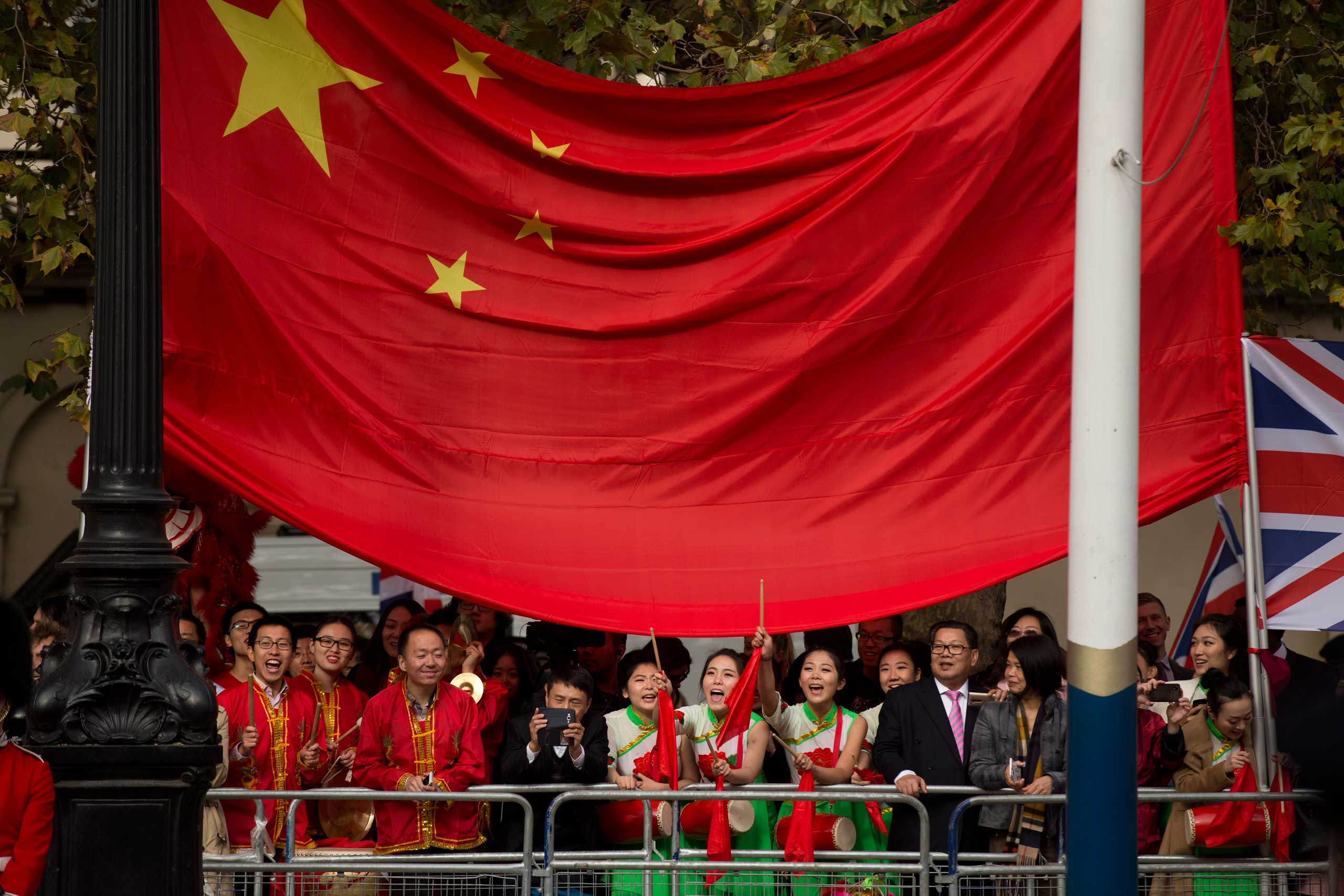 Supporters of President Xi stand under a large Chinese flag before the President passes by on a horse-drawn carriage with Britain's Queen Elizabeth II on the Mall en route to Buckingham Palace in London,  Oct. 20, 2015. (Matt Dunham—AP)
