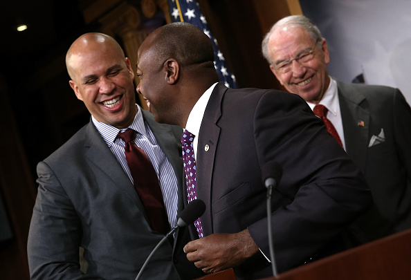 Sen. Corey Booker (L) (D-NJ) hugs Sen. Tim Scott (C) (R-SC) as Senate Judiciary Committee Chairman Sen. Chuck Grassley (R) (R-IA) looks on during a press conference at the U.S. Capitol announcing a bipartisan effort to reform the criminal justice system October 1, 2015 in Washington, DC.