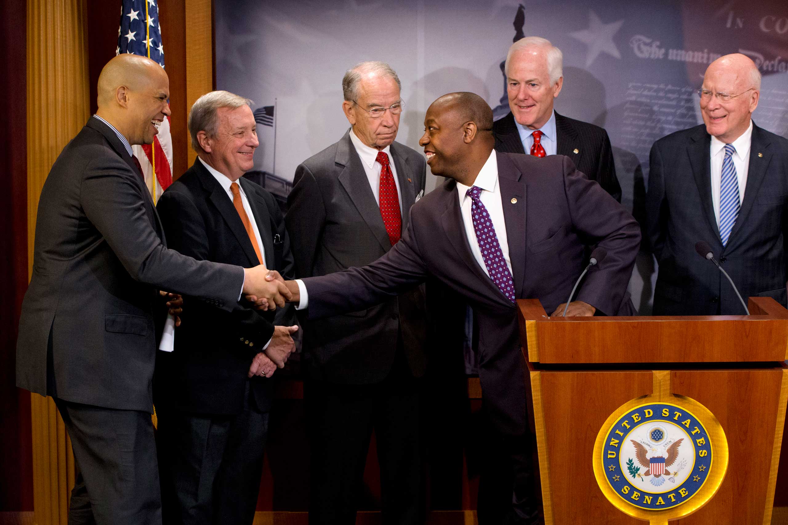 Sen. Tim Scott, R-S.C., leans from the podium to shake hands with Sen. Cory Booker, D-N.J., while speaking about criminal justice reform with a bipartisan group of senators during a news conference on Capitol Hill in Washington, Oct. 1, 2015, (Jacquelyn Martin—AP)