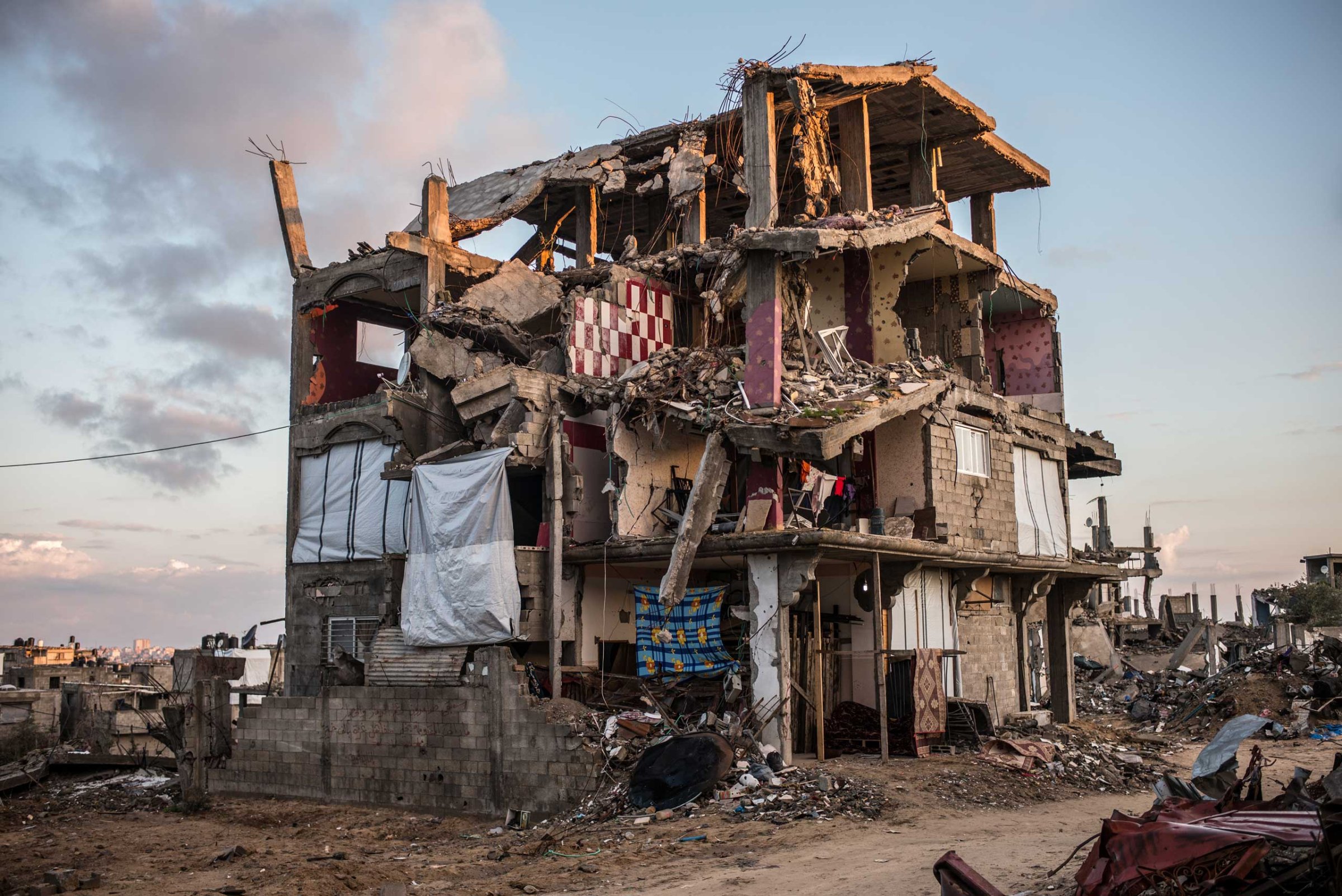 A partially destroyed building in Shejaiya, a neighborhood district of the Palestinian city of Gaza. Some family tried to replace the missing walls of their apartments with blankets. Shejaiya, Gaza. December 2014.